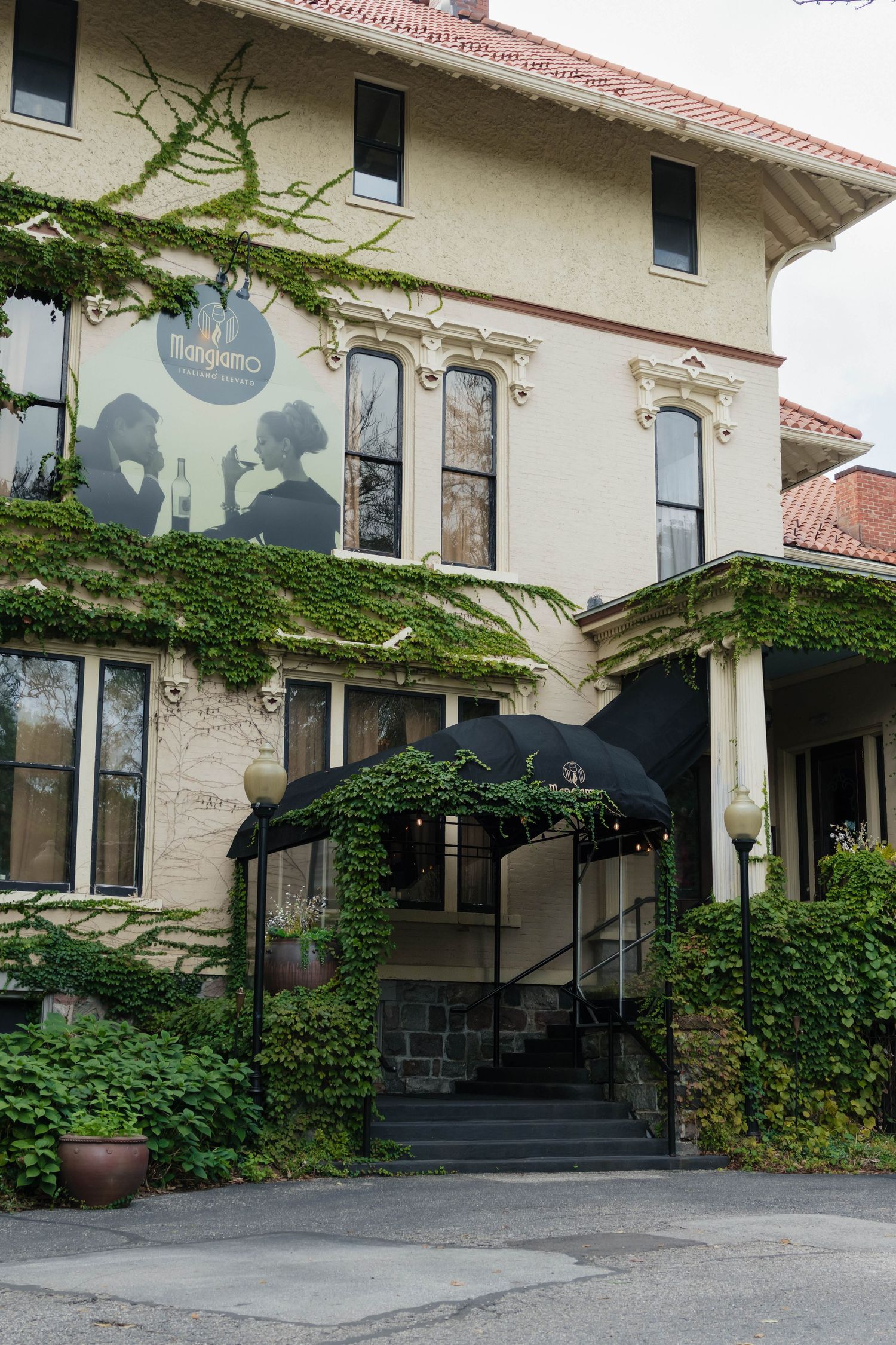 Elegant ivy-covered wedding venue exterior with black awning entrance and vintage architectural details.