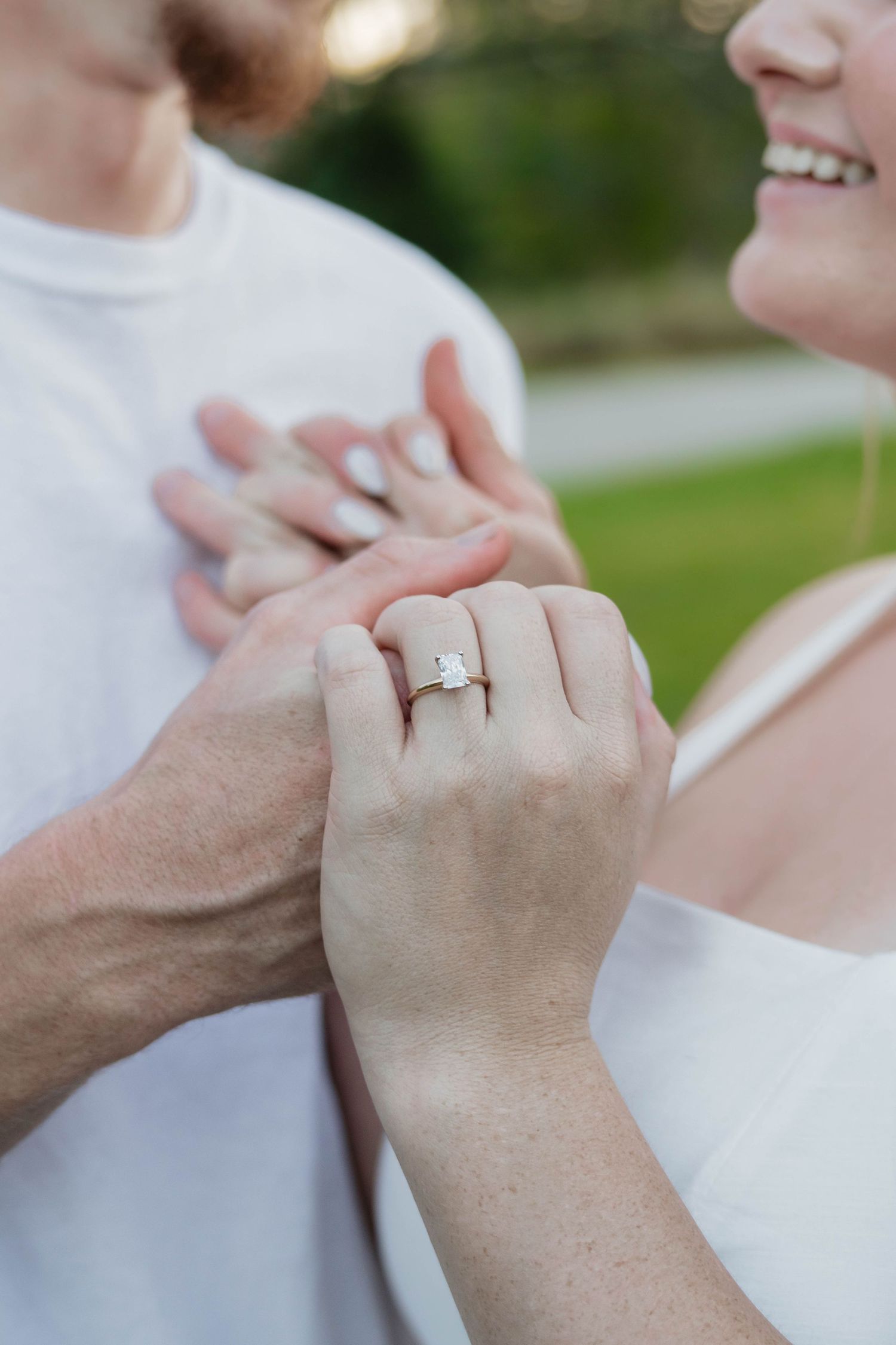 Close-up of an engaged couple holding hands, showcasing a stunning diamond engagement ring.