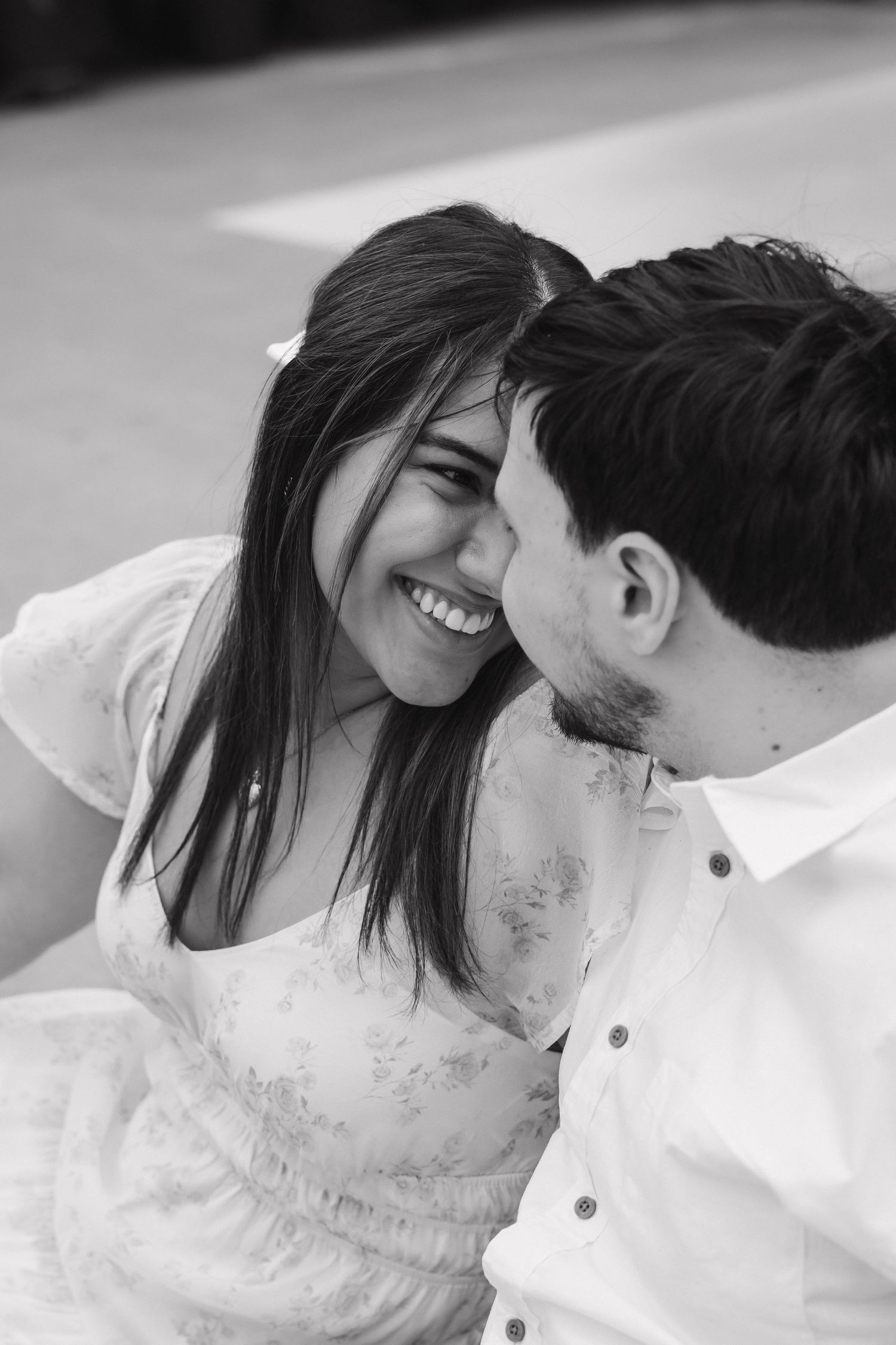 Black and white close-up of laughing couple sharing an intimate moment during greenhouse engagement session.