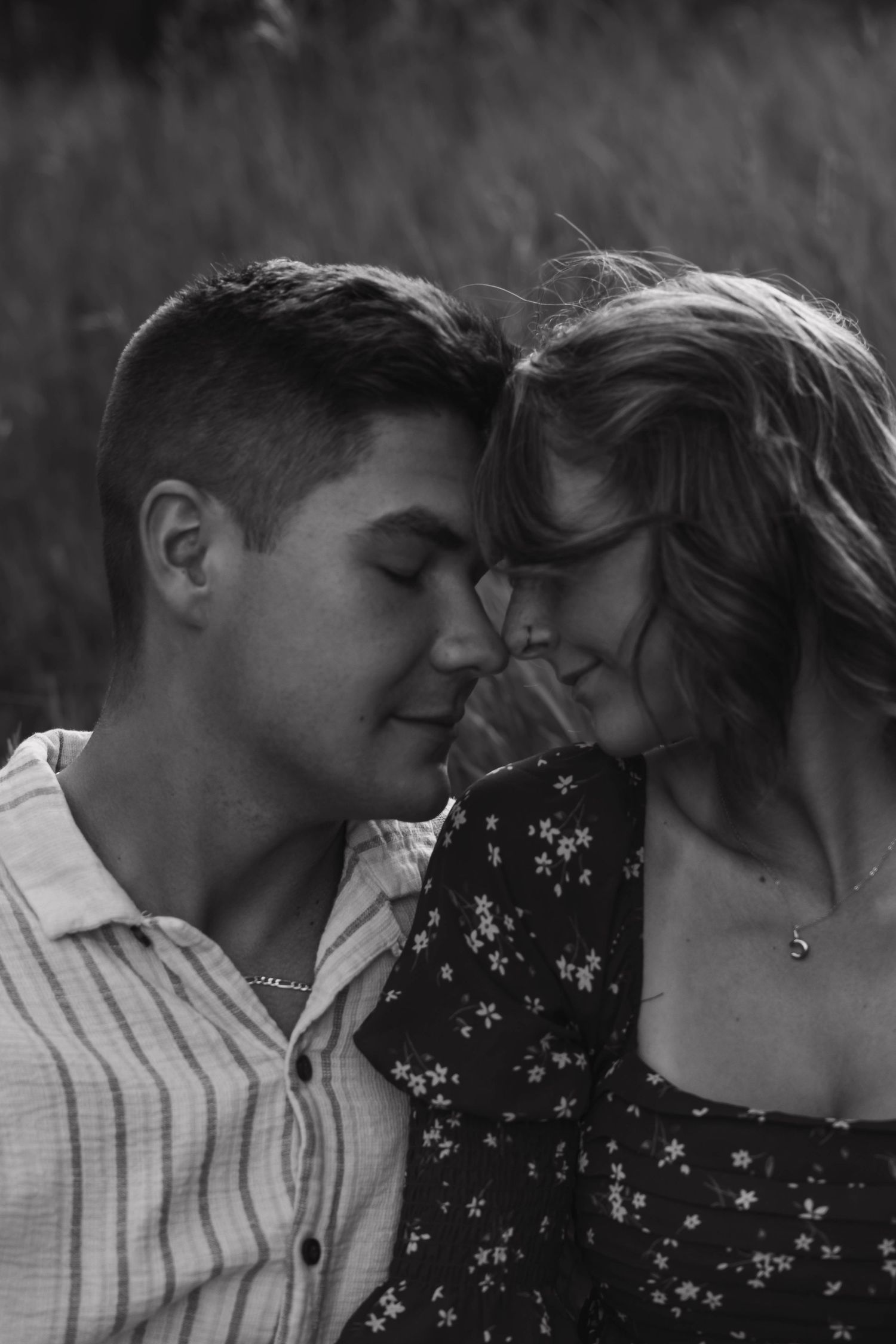 Black and white photo of a couple touching foreheads tenderly, eyes closed, sharing a romantic intimate moment.
