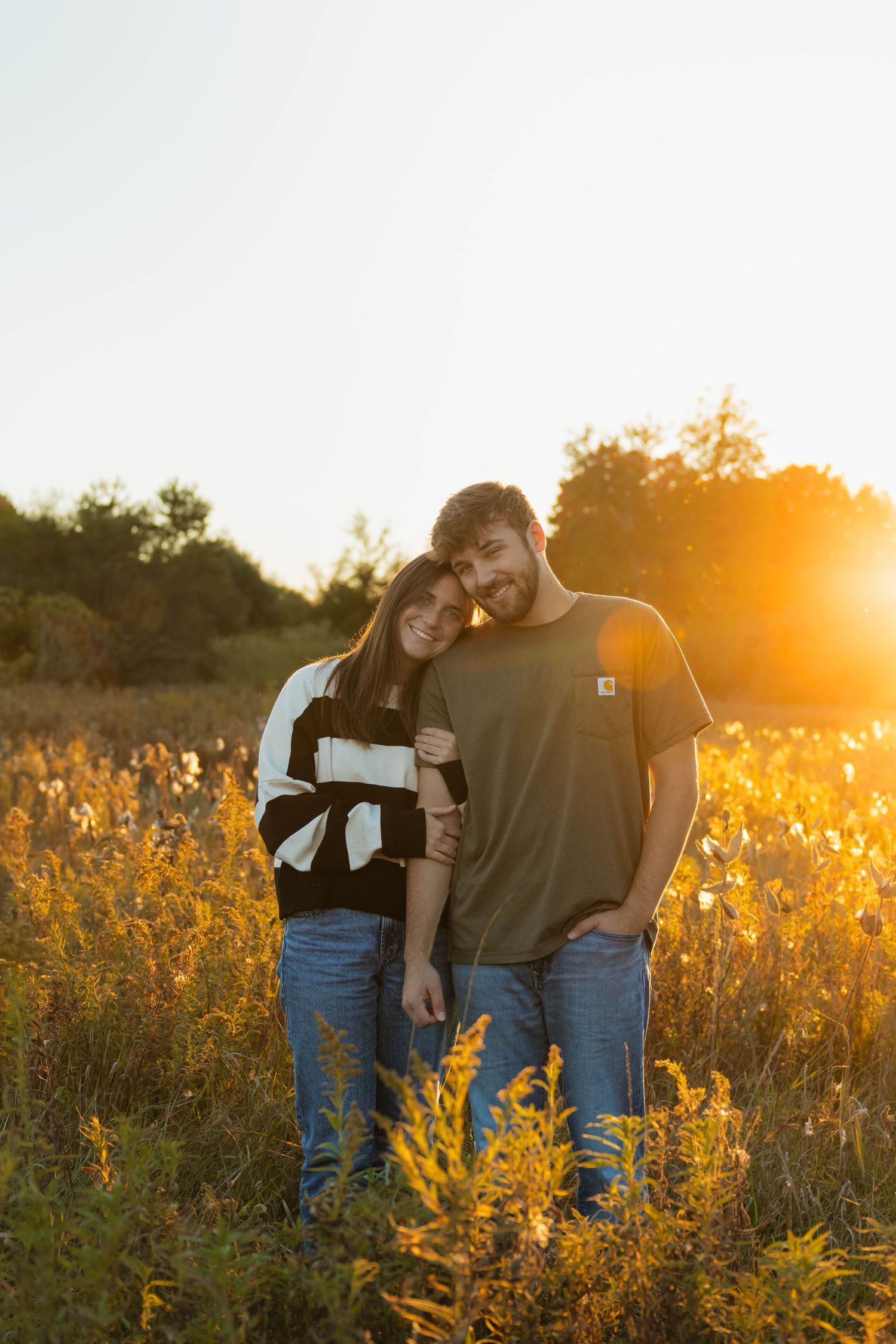 Couple embracing in a wildflower field bathed in warm golden sunset light.