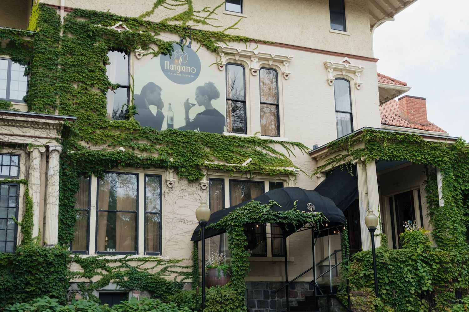 Ivy-covered historic stone mansion venue with arched windows and black awning entrance.
