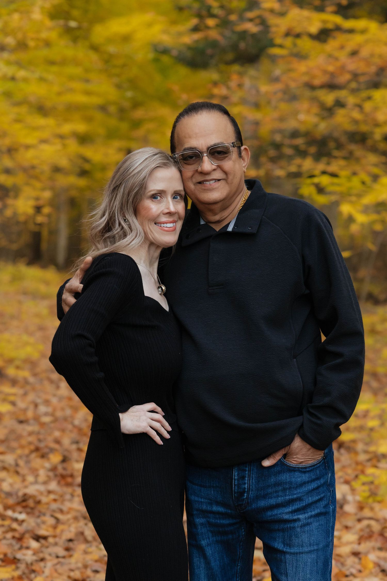 Couple embracing outdoors with warm golden autumn foliage in the background during fall portrait.