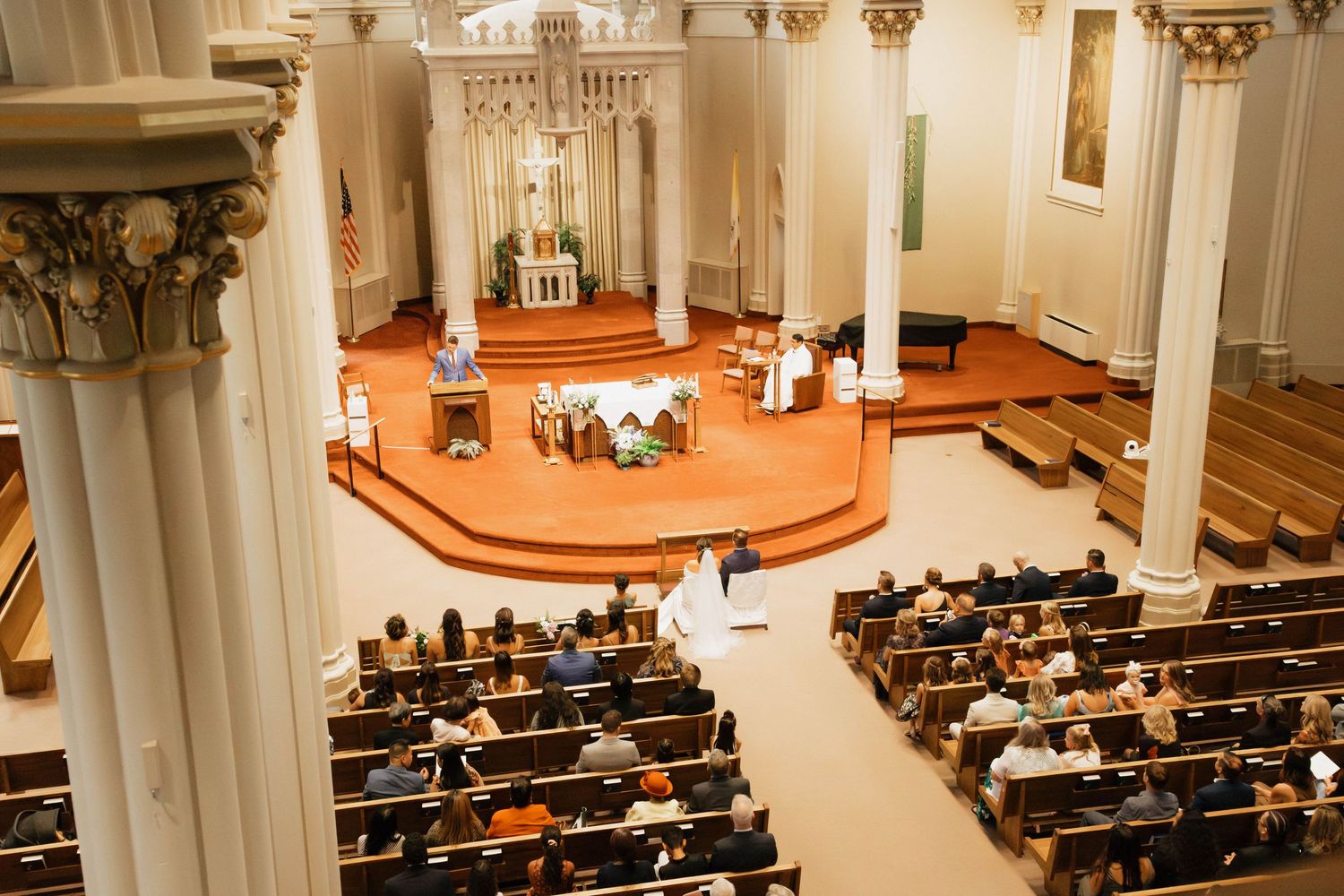Aerial view of a traditional church wedding ceremony with guests seated in wooden pews and couple at the altar.