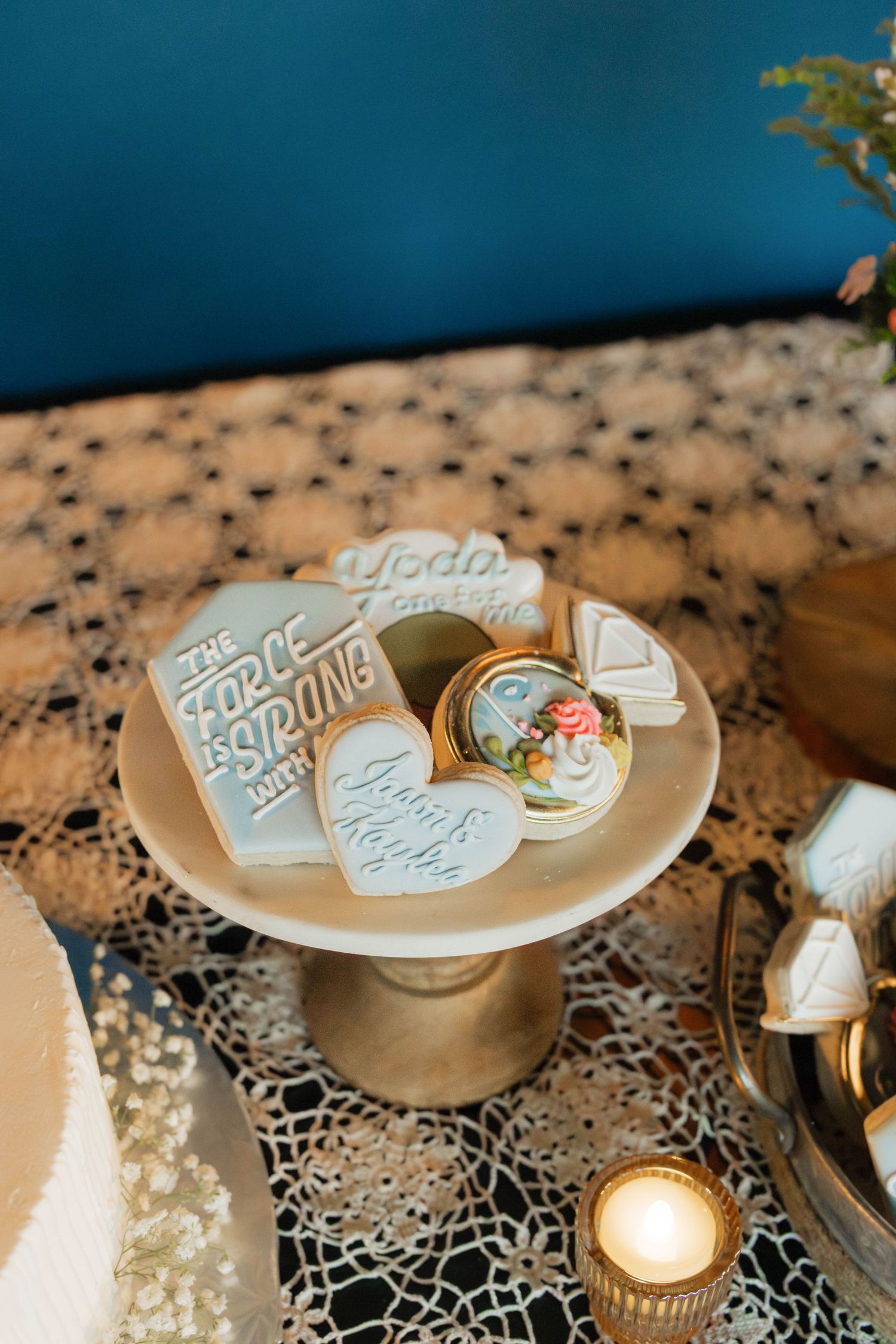 Decorated wedding cookies on a gold cake stand featuring Star Wars and romantic themes with couple's names.