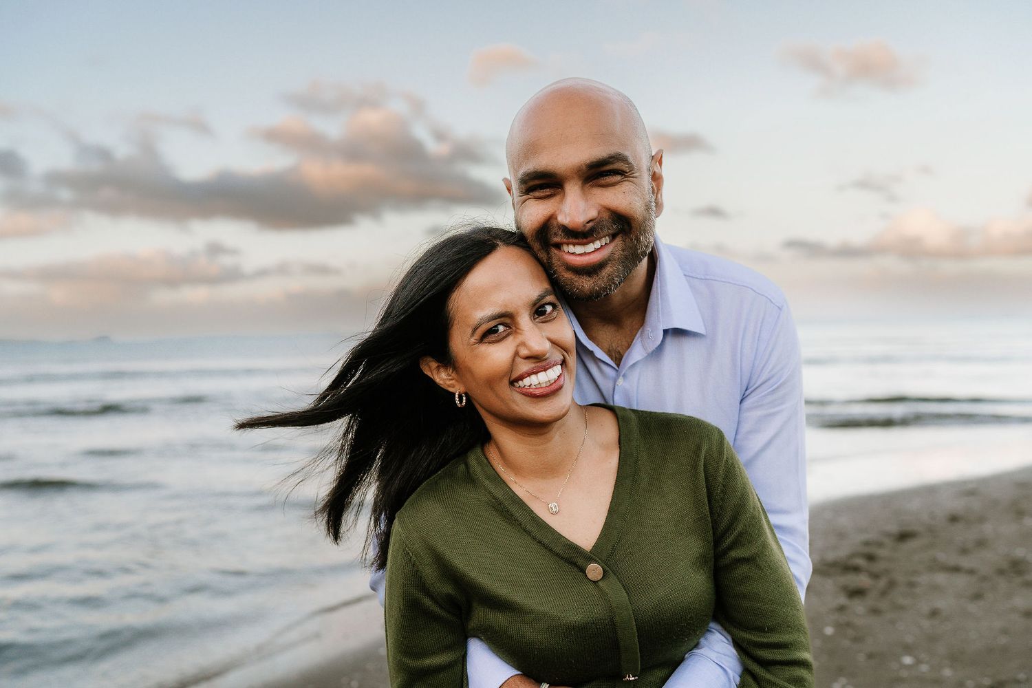young couple laughing in on the beach during family photo session in auckland