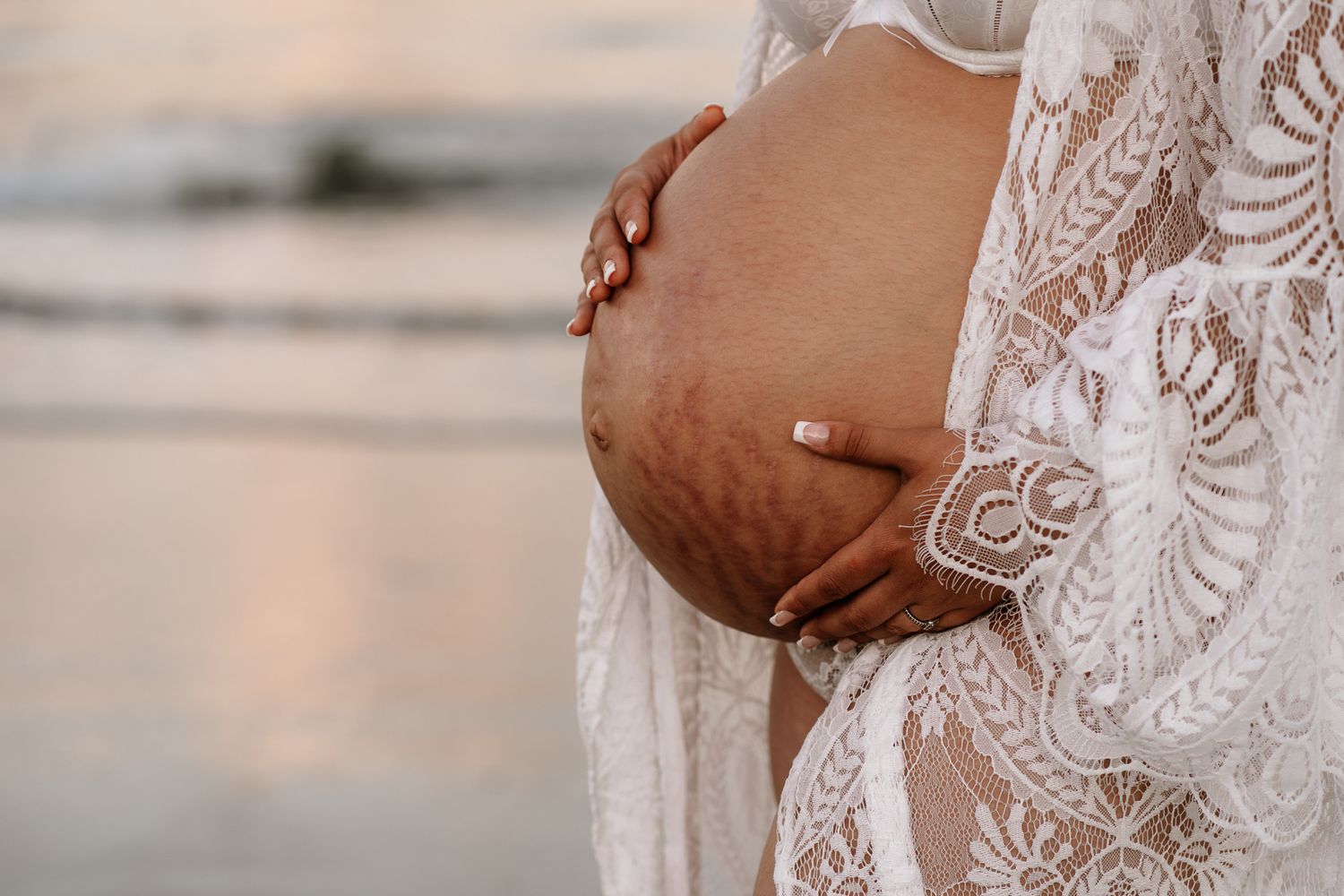 woman holding her baby belly at sunset