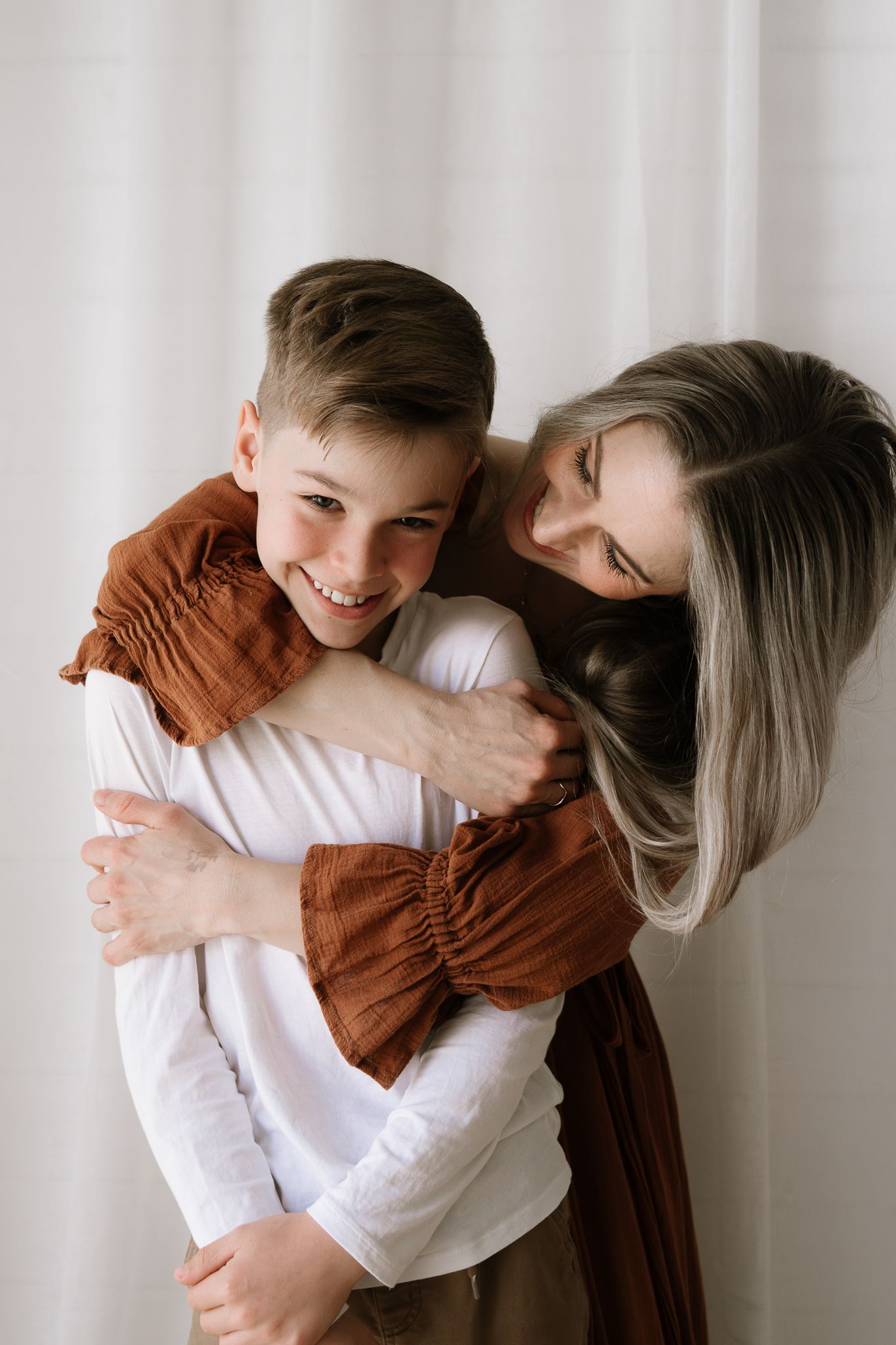 Family studio session with young children, capturing playful and tender moments in a softly lit, minimal setting.