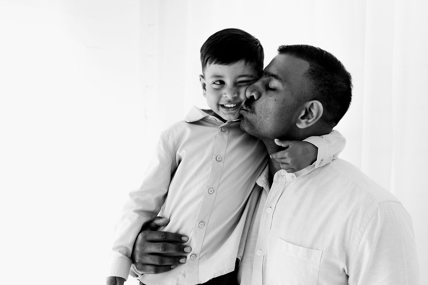Family studio session with young children, capturing playful and tender moments in a softly lit, minimal setting.
