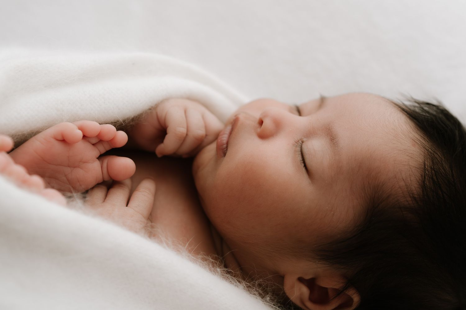 newborn sleeping baby wrapped in white blanket during studio session in Auckland close up