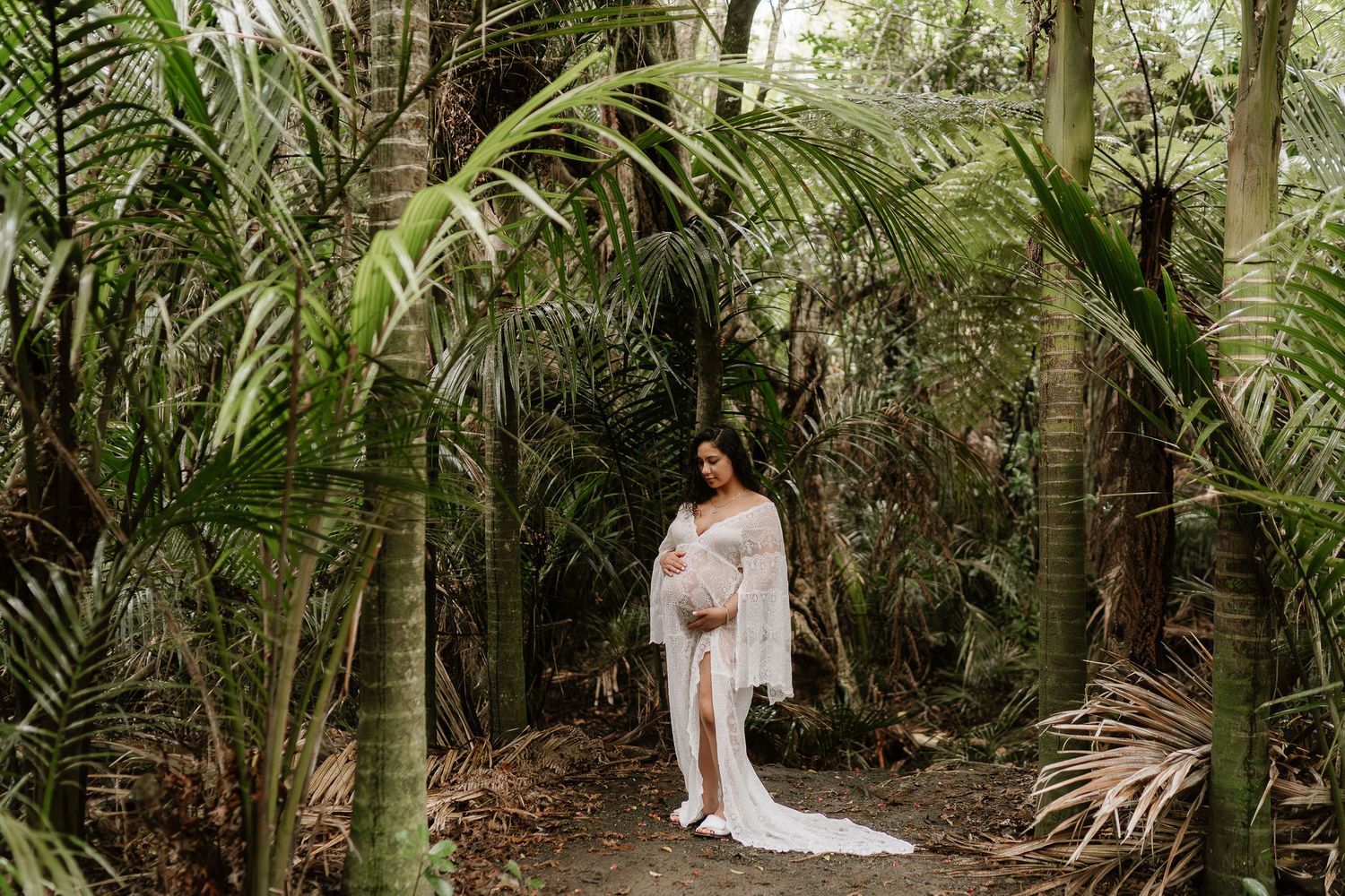 pregnant woman surrounded by native bush, soft light filtering through trees