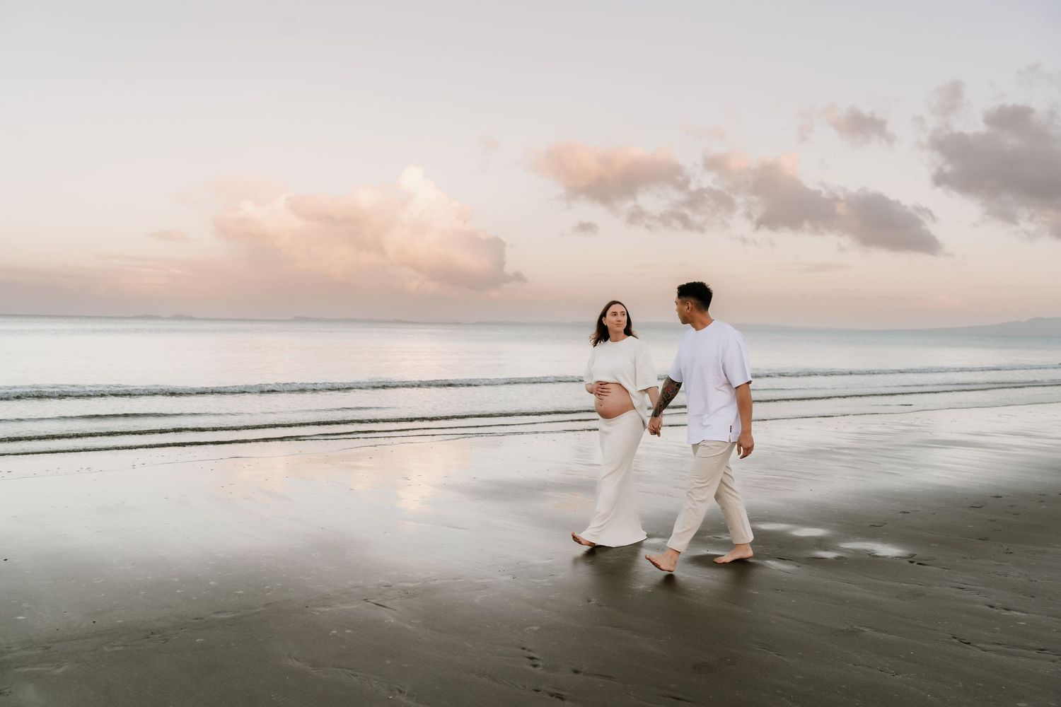 Stunning maternity reflections in the tide at sunset. Bold and modern beach photography by Little Wild Ones, Auckland.