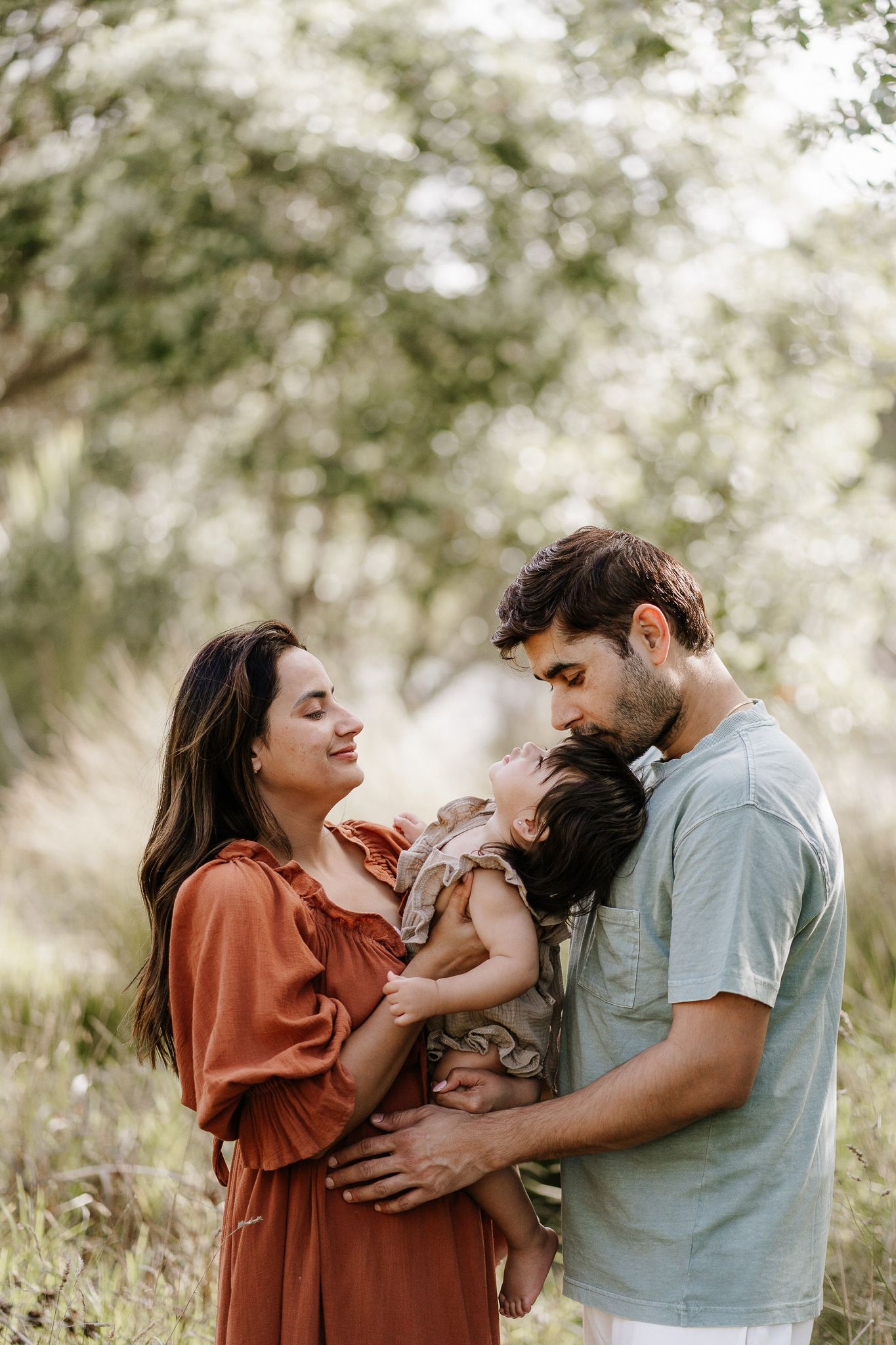 mum dad and daughter in trees having family photos