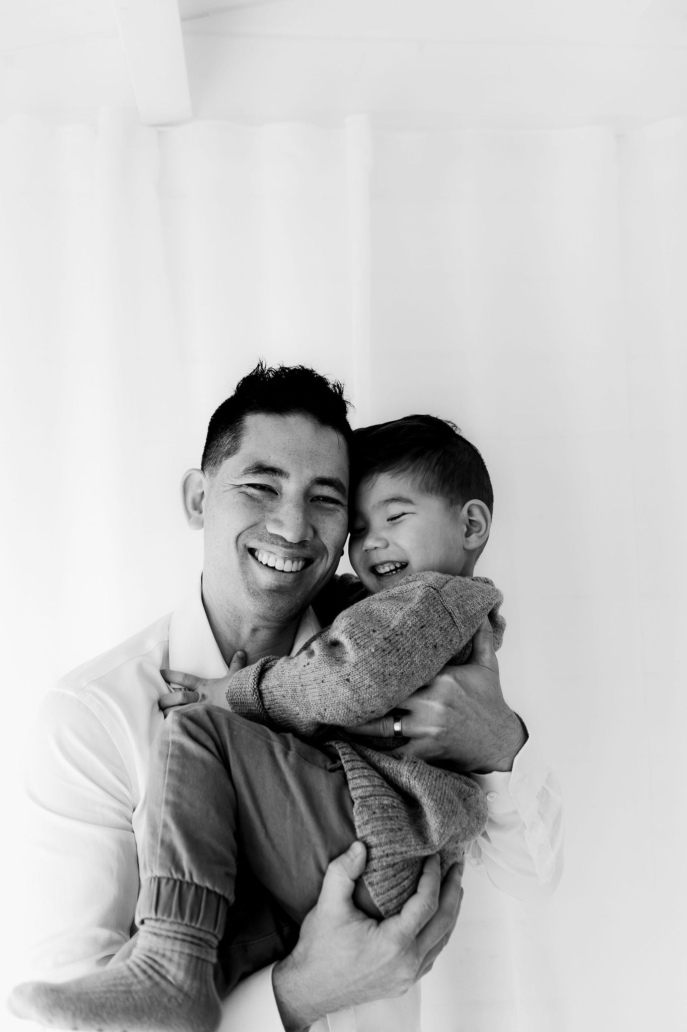 dad cuddling laughing son during family photoshoot