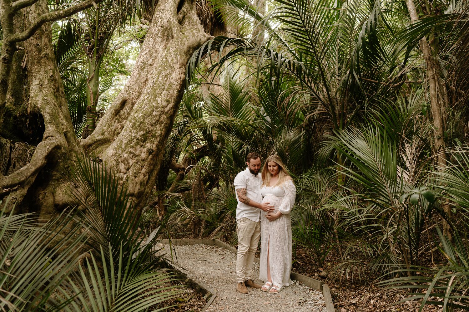 pregnant woman surrounded by native bush, soft light filtering through trees