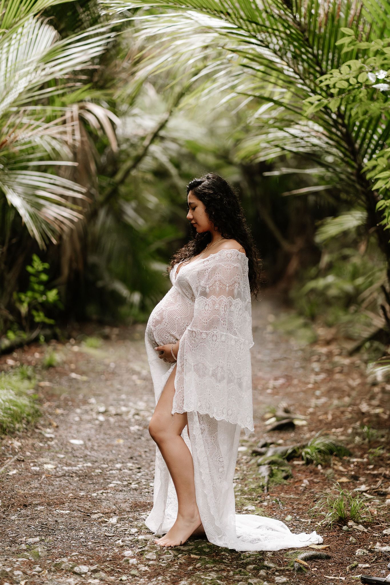 pregnant woman surrounded by native bush, soft light filtering through trees