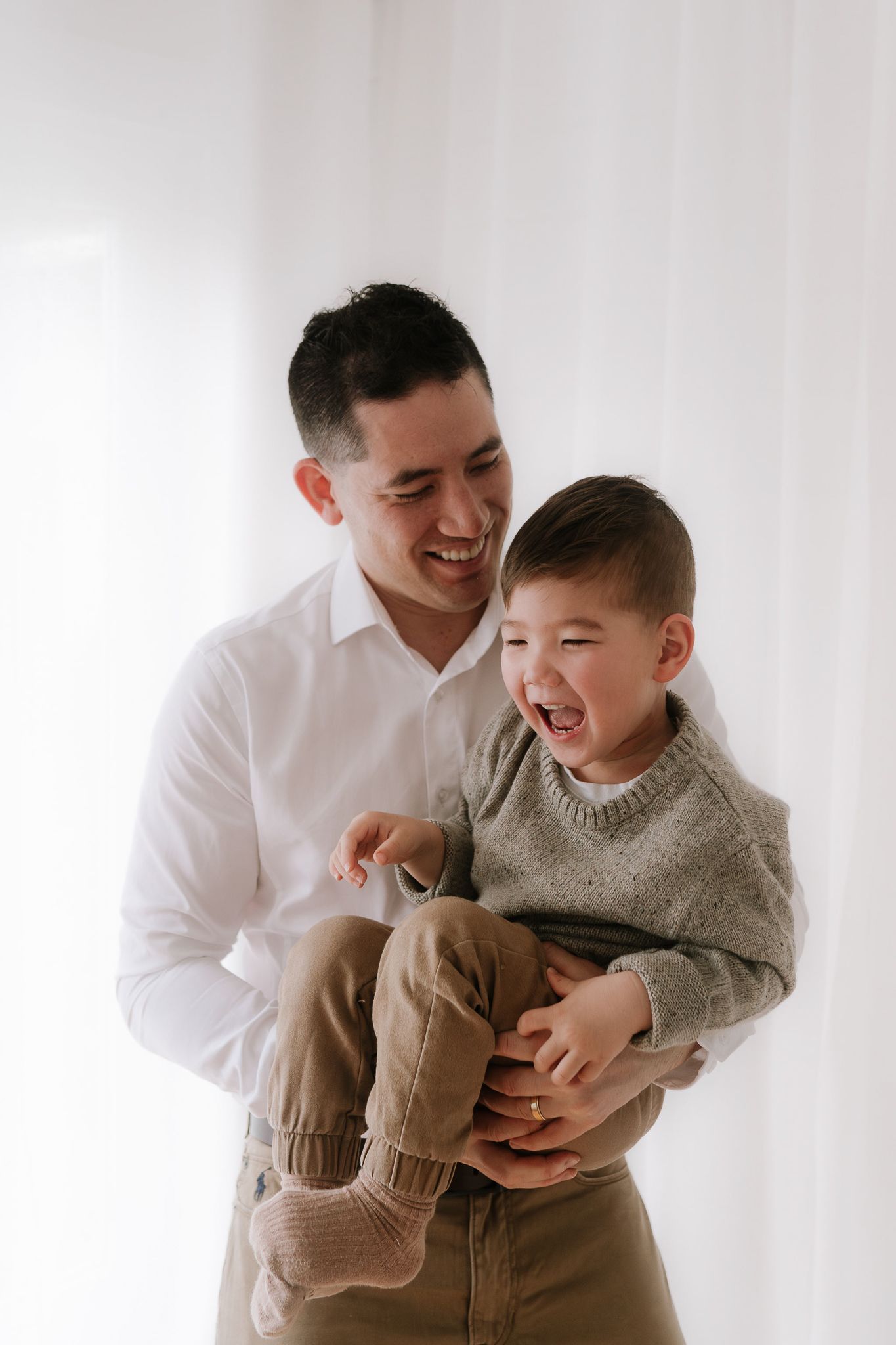 Family studio session with young children, capturing playful and tender moments in a softly lit, minimal setting.