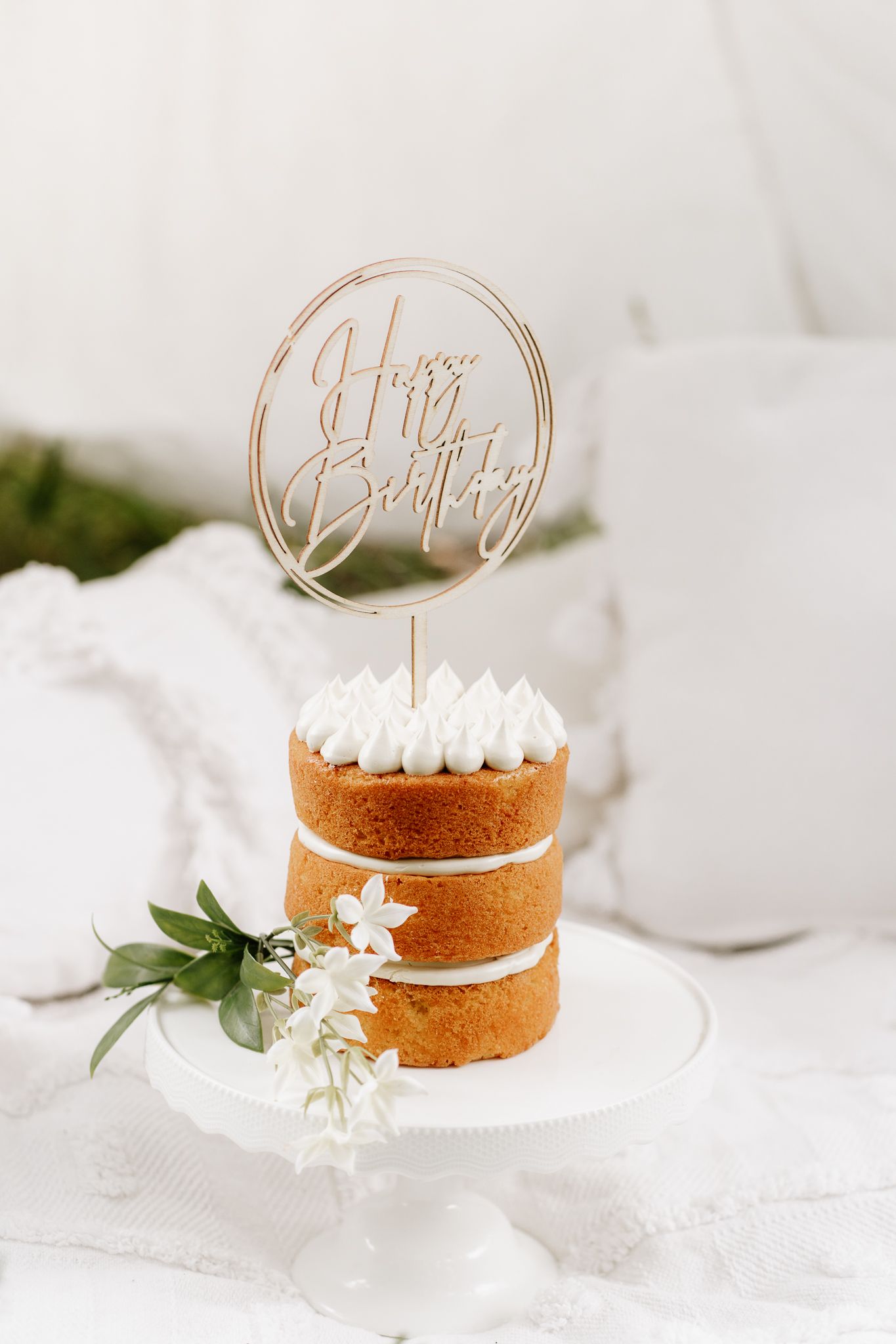 Outdoor cake smash session with a baby seated in front of a teepee, surrounded by long grass. A whimsical, natural setting with playful, mes