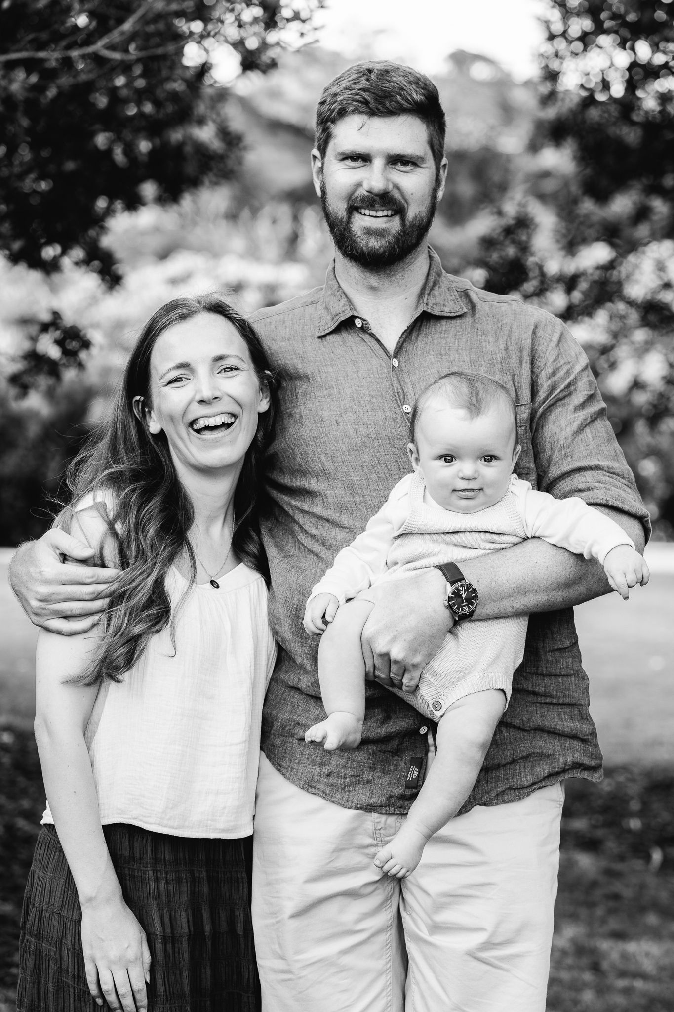 black and white photo of a family photo session dad holding baby and mum