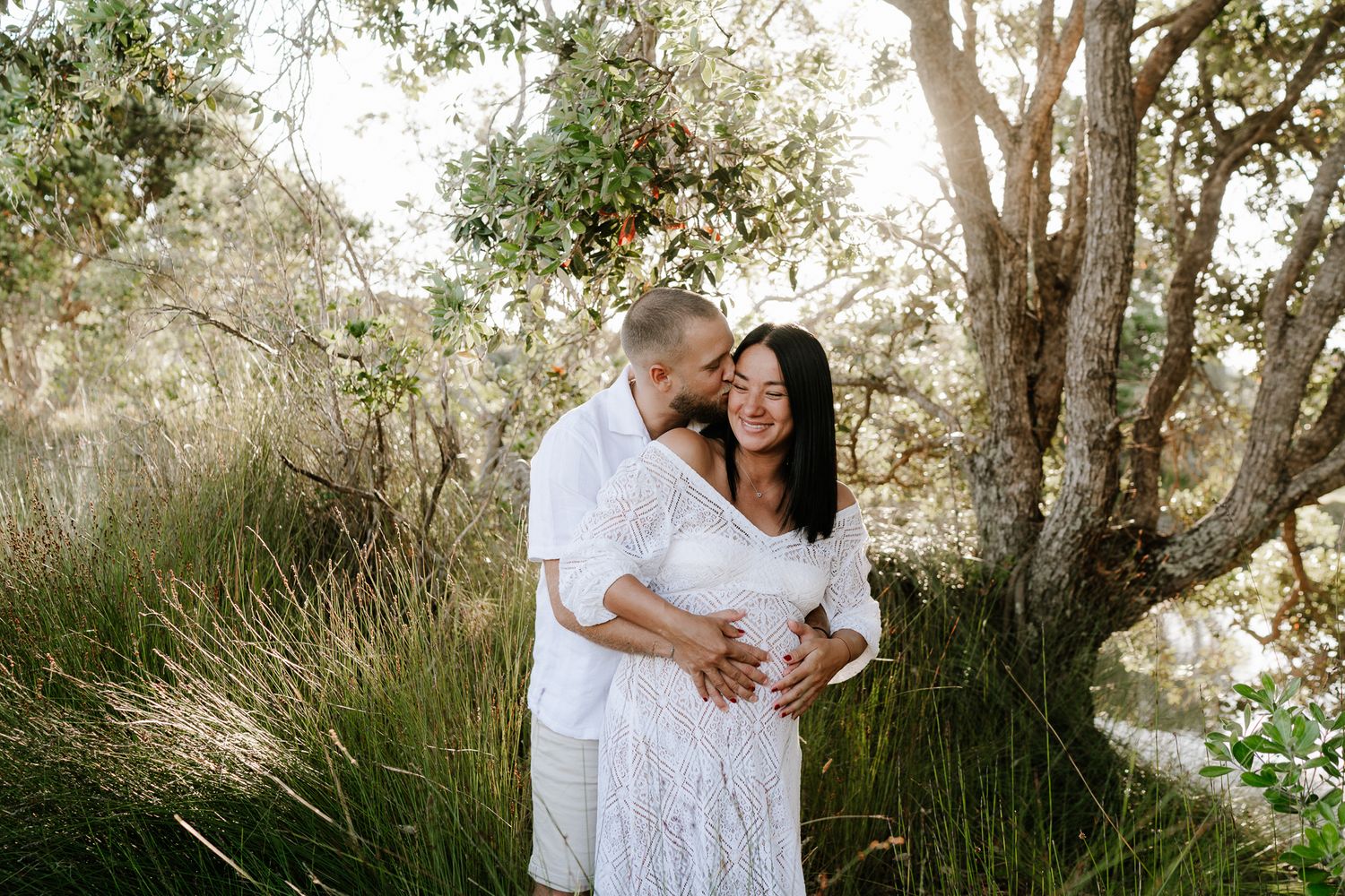 pregnant woman surrounded by native bush, soft light filtering through trees