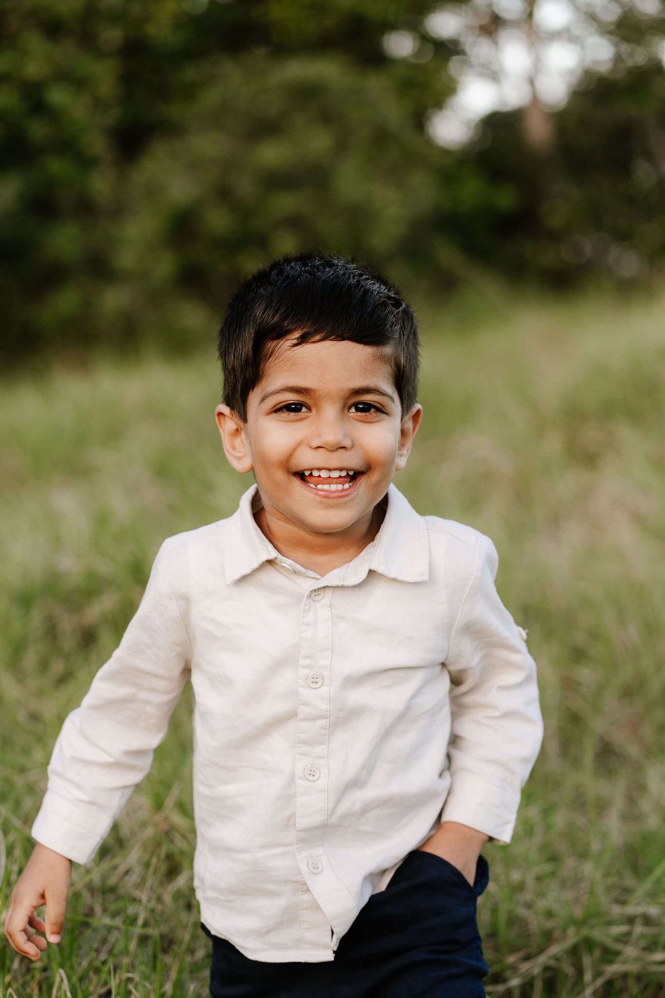 young boy laughing in long grass during family photo session in auckland