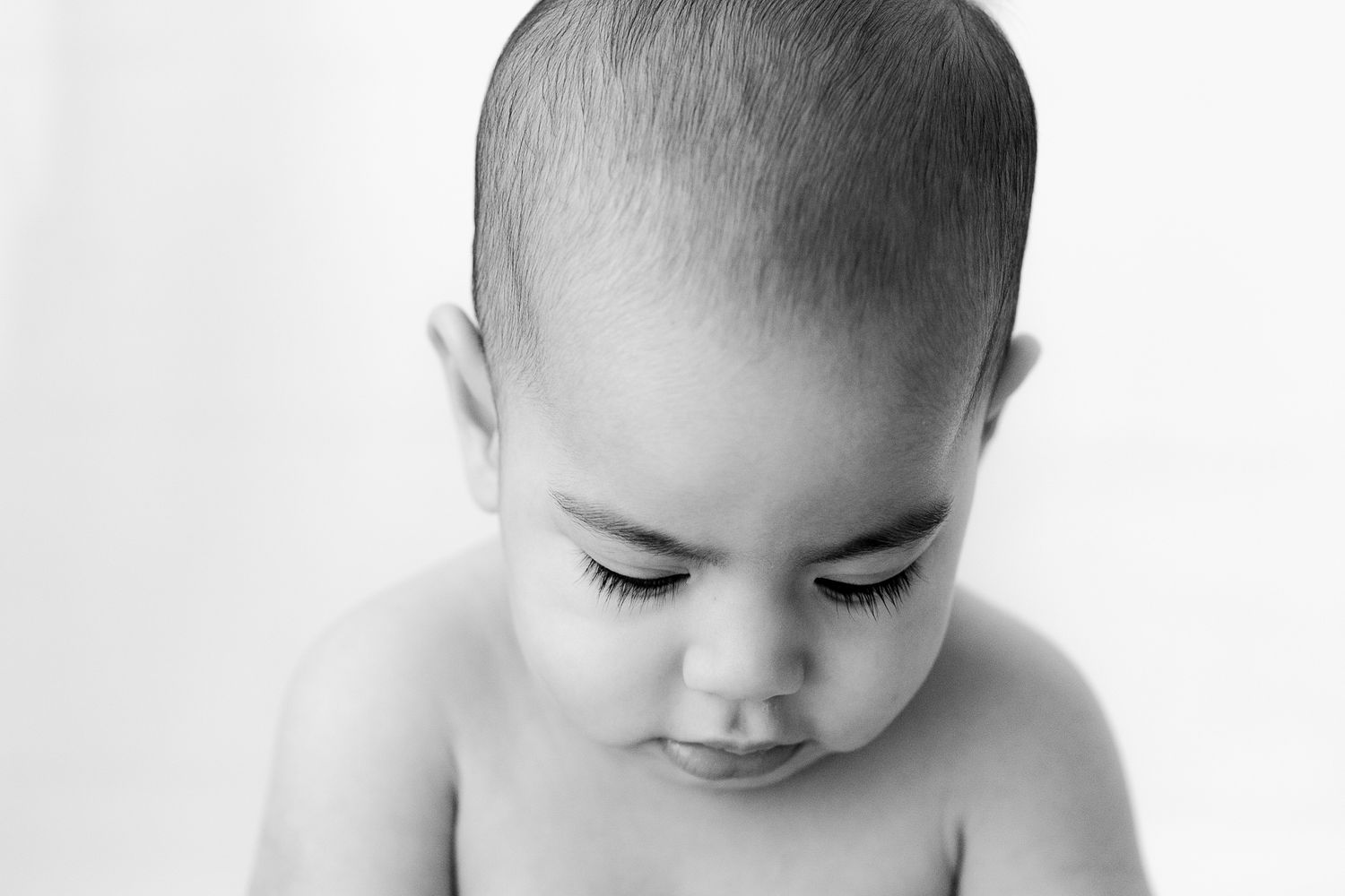 black and white photo of baby looking down