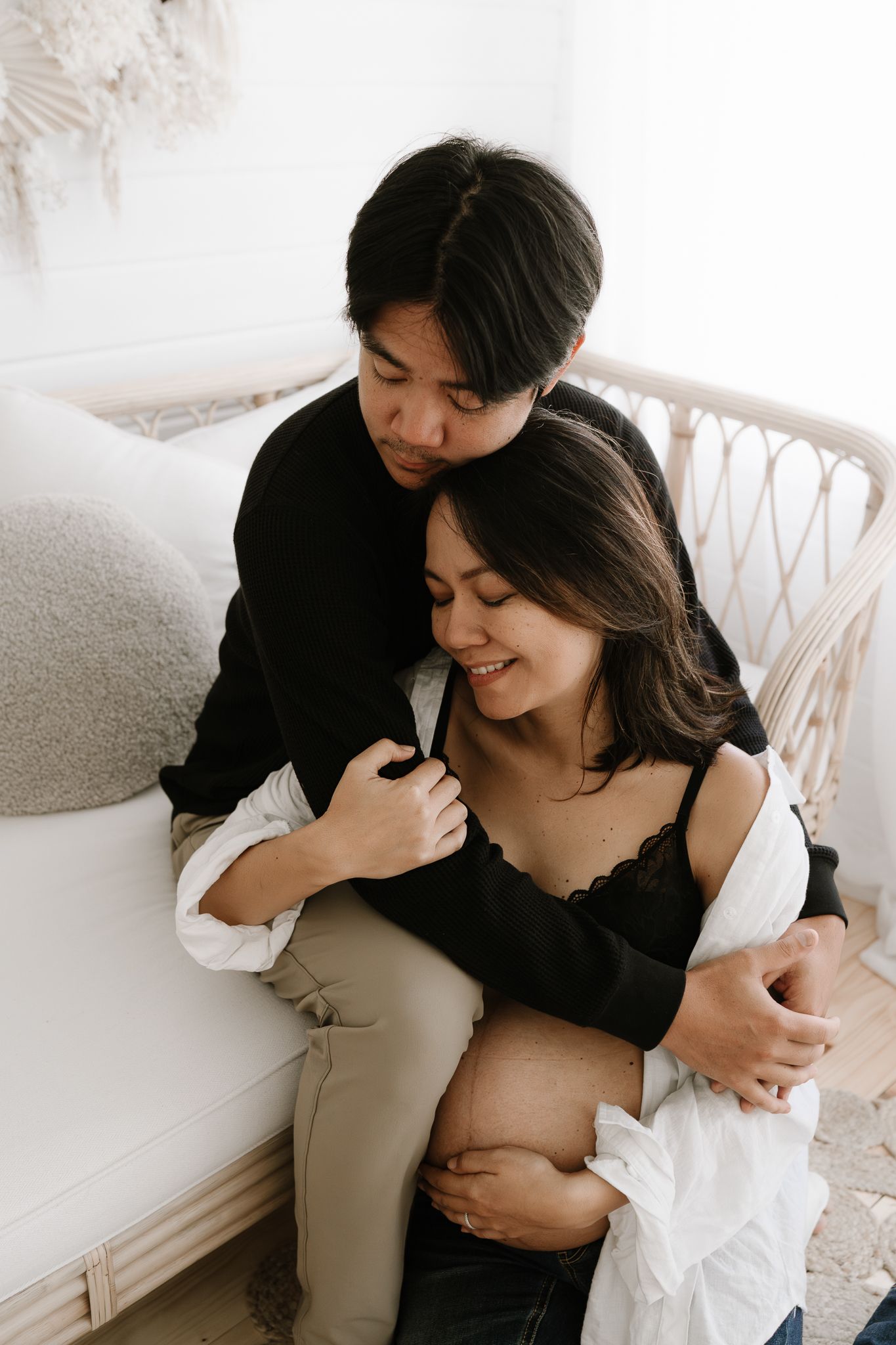 husband hugs pregnant wife in studio setting