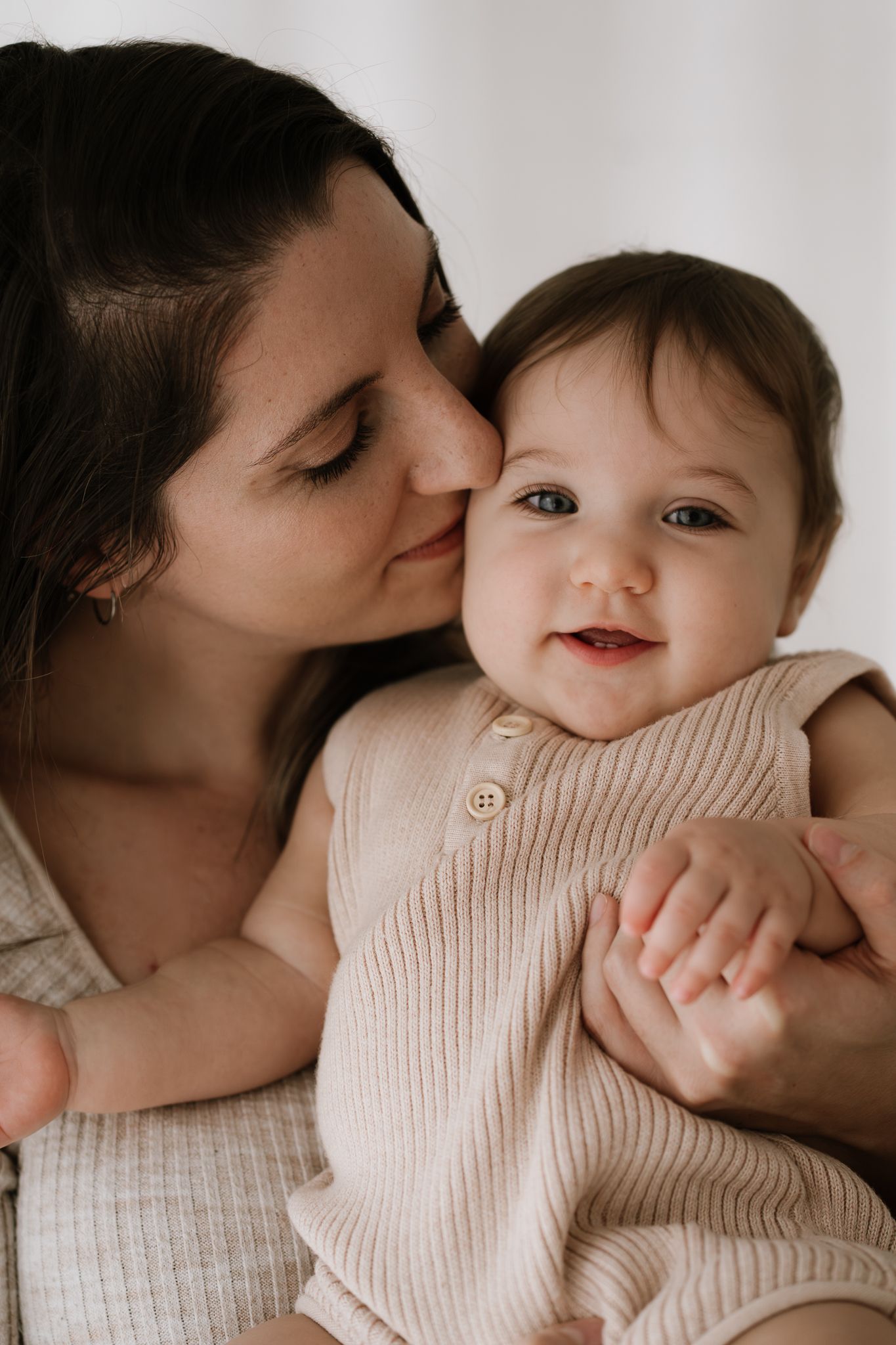 mum kissing baby on cheek in studio family session