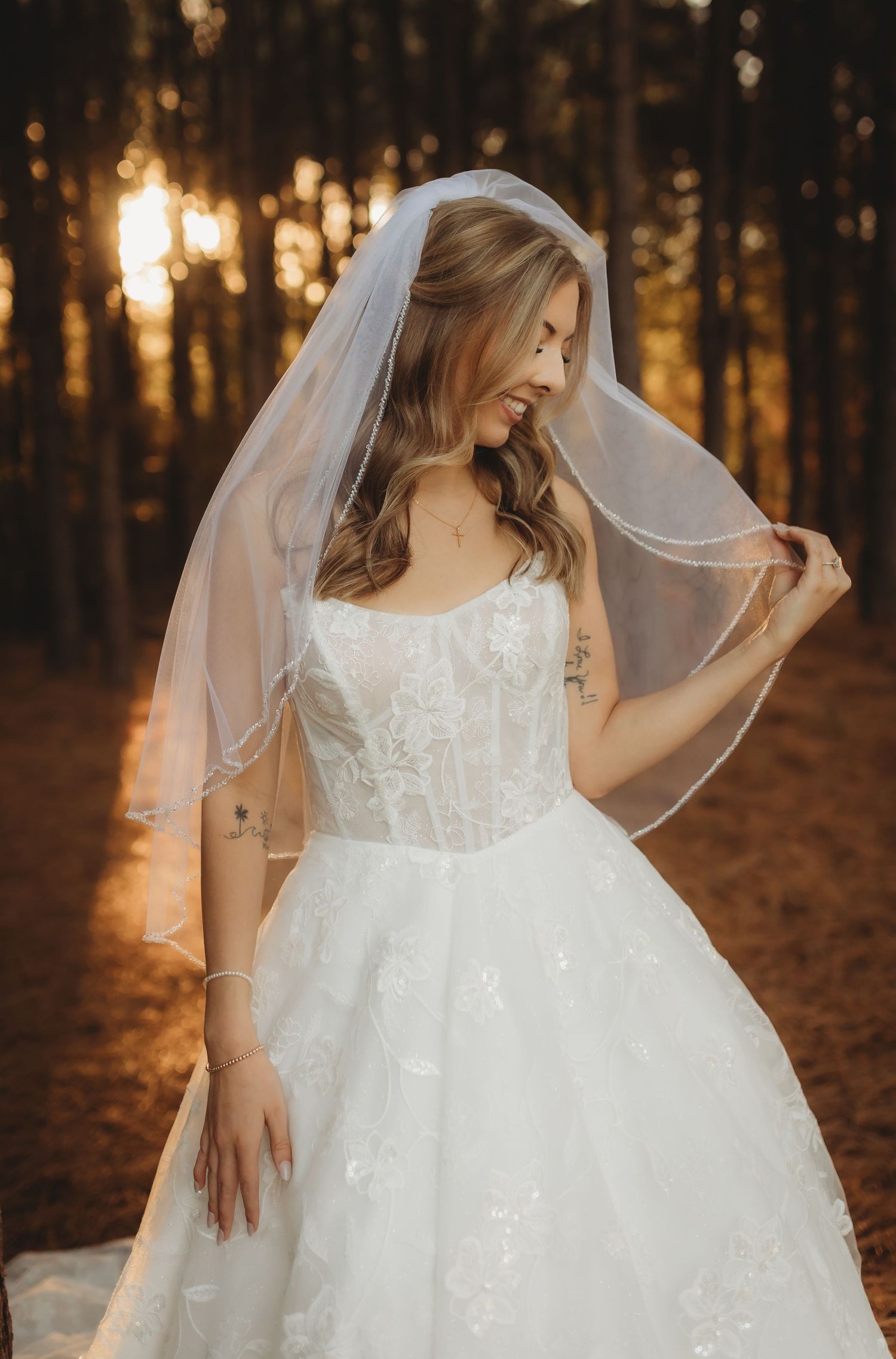 Ethereal white lace flower girl dress with tulle skirt photographed in a sunlit forest at golden hour.