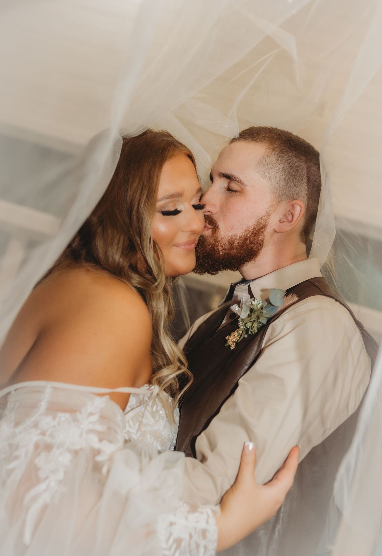 A romantic wedding couple shares intimate kisses under a white veil in a series of tender moments.