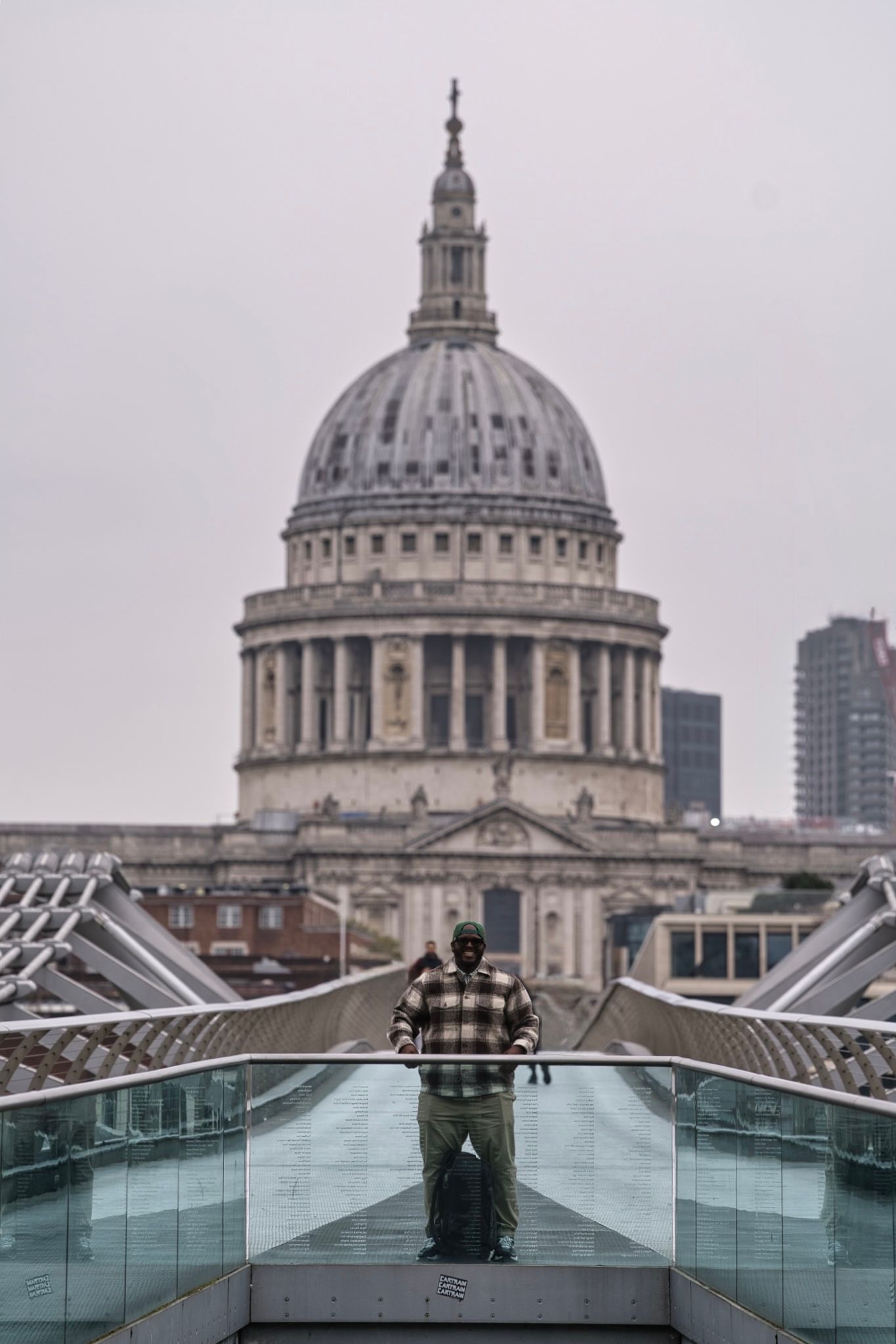 St Paul's Cathedral dome viewed from Millennium Bridge with a visitor silhouetted in foreground.