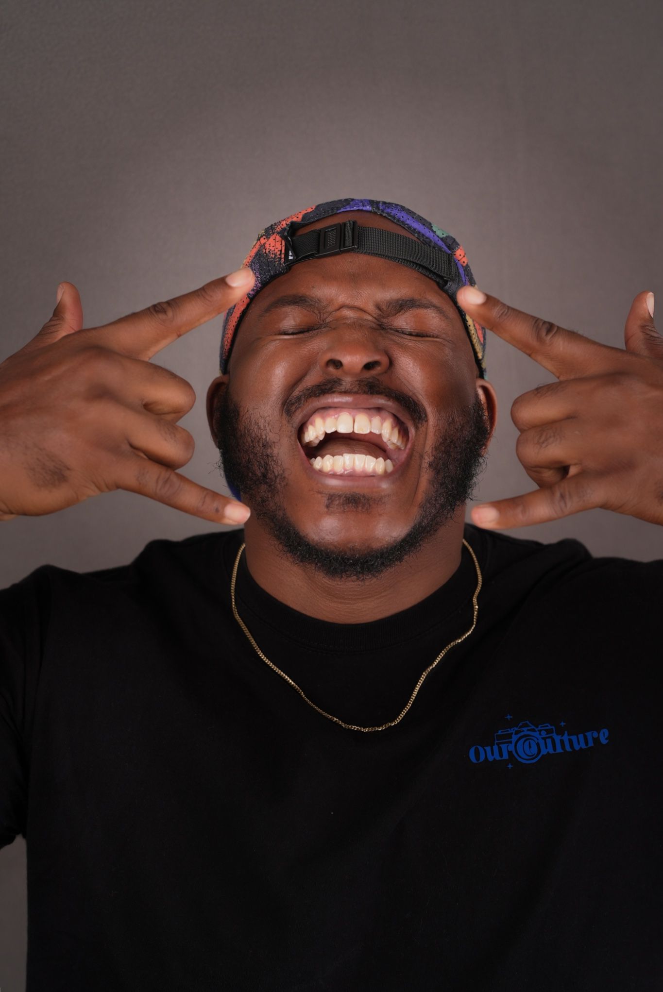 Person wearing headphones and black t-shirt expressing joy with animated gesture.