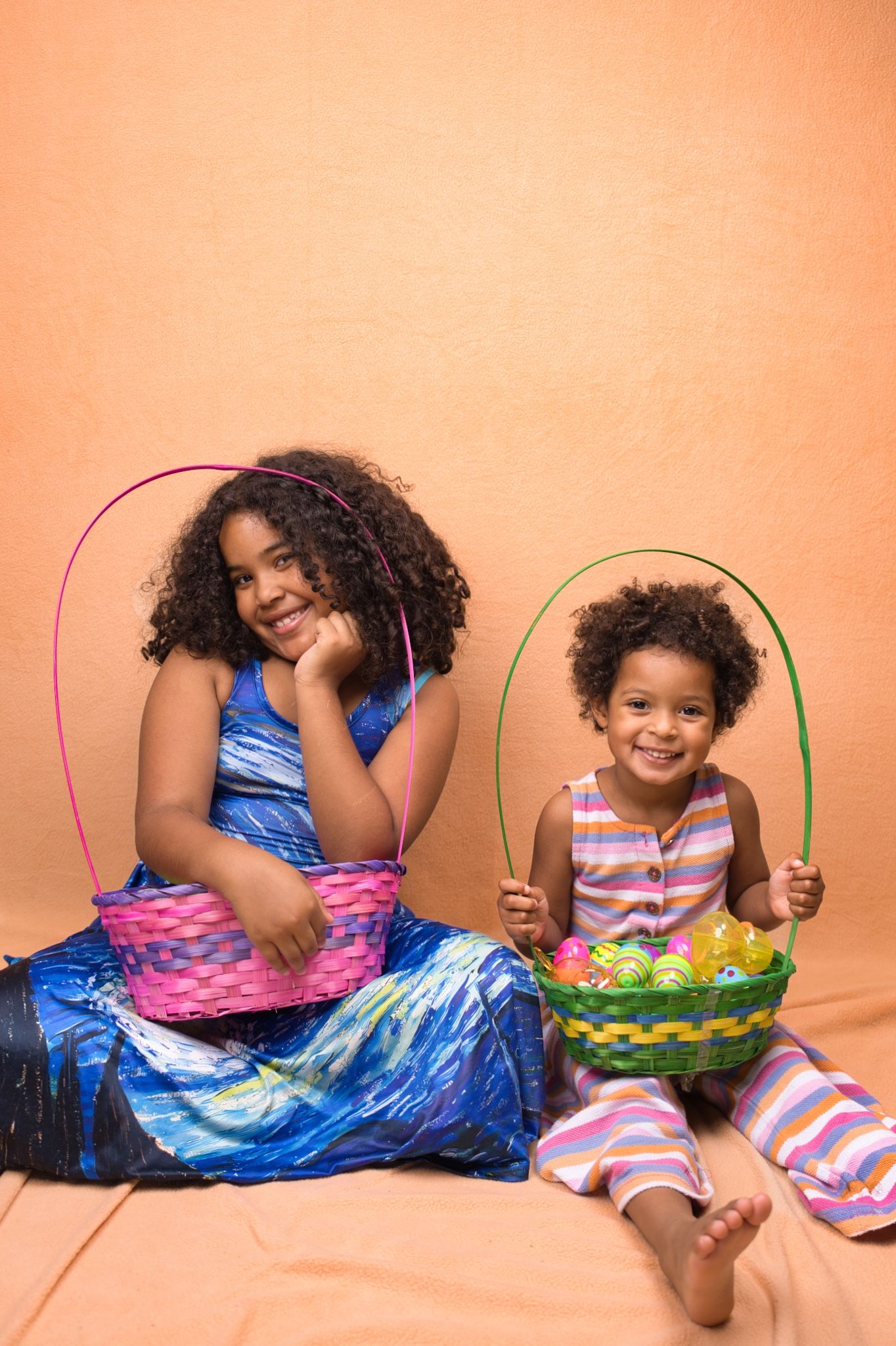 Children posing with Easter baskets against peach colored background.