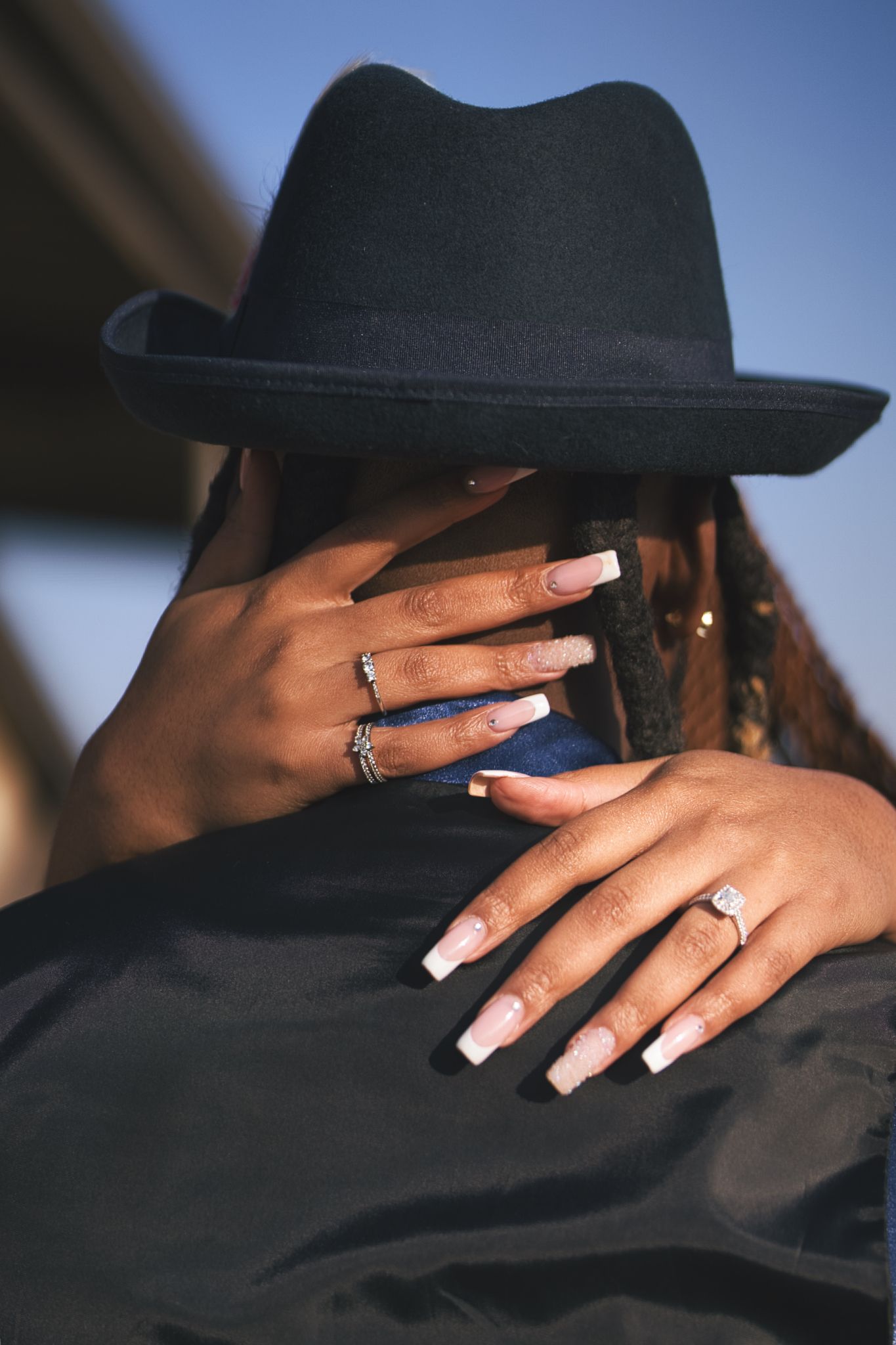 A series of photos showing hands with white manicured nails against black clothing and hat in artistic poses.