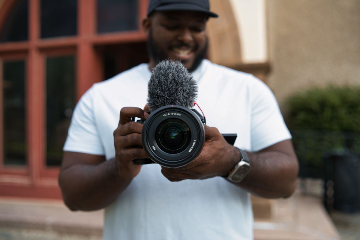 A photographer holding a professional camera takes a self-portrait reflection.