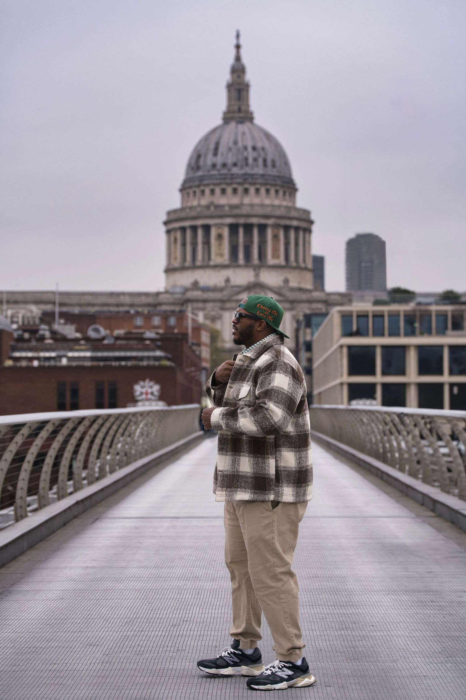 A person in casual wear stands on Millennium Bridge with St Paul's Cathedral in London.