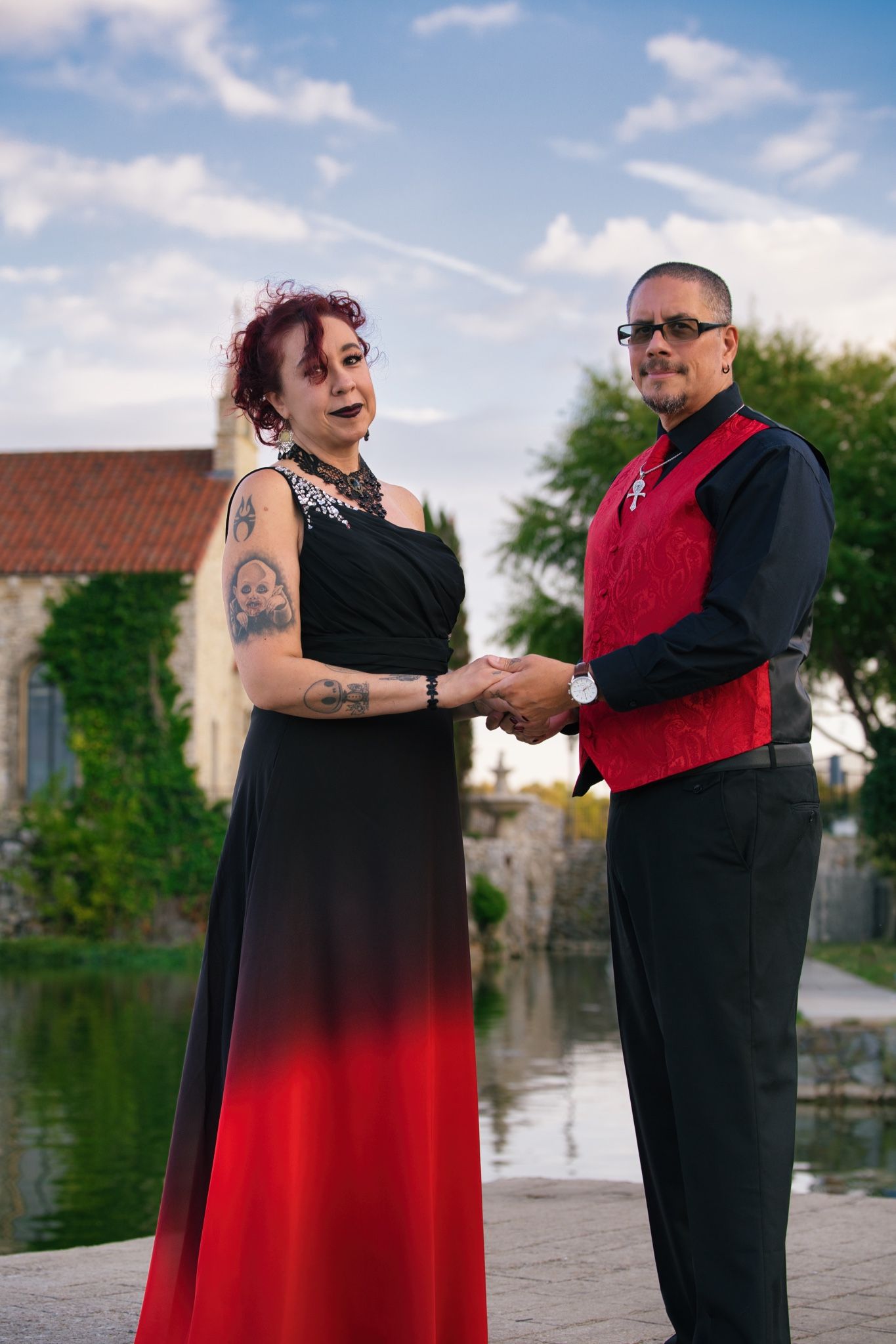 Couple in formal attire holds hands on waterfront deck during outdoor celebration.