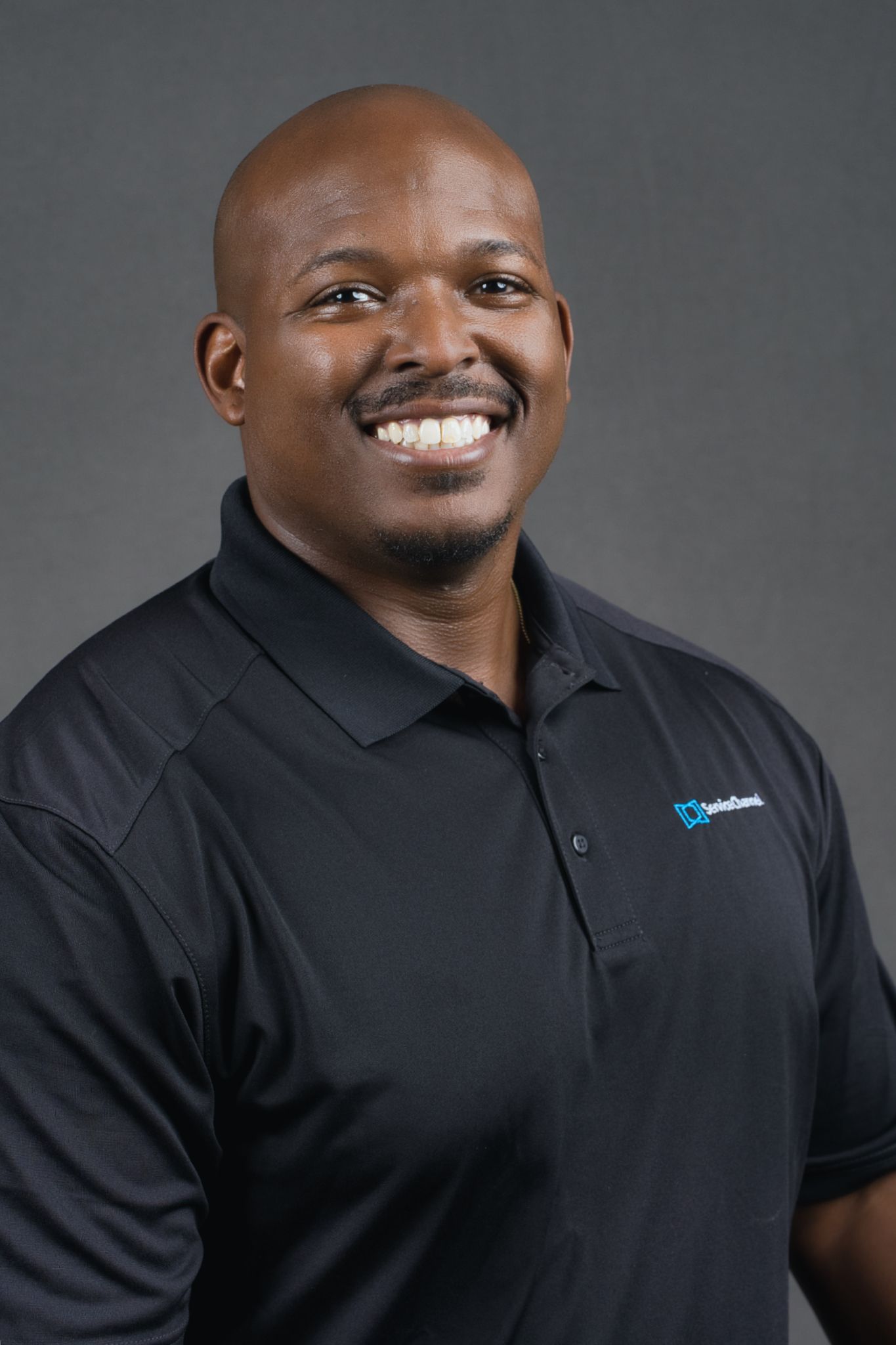 Professional headshots showing warm expressions against a gray backdrop while wearing a black polo shirt.