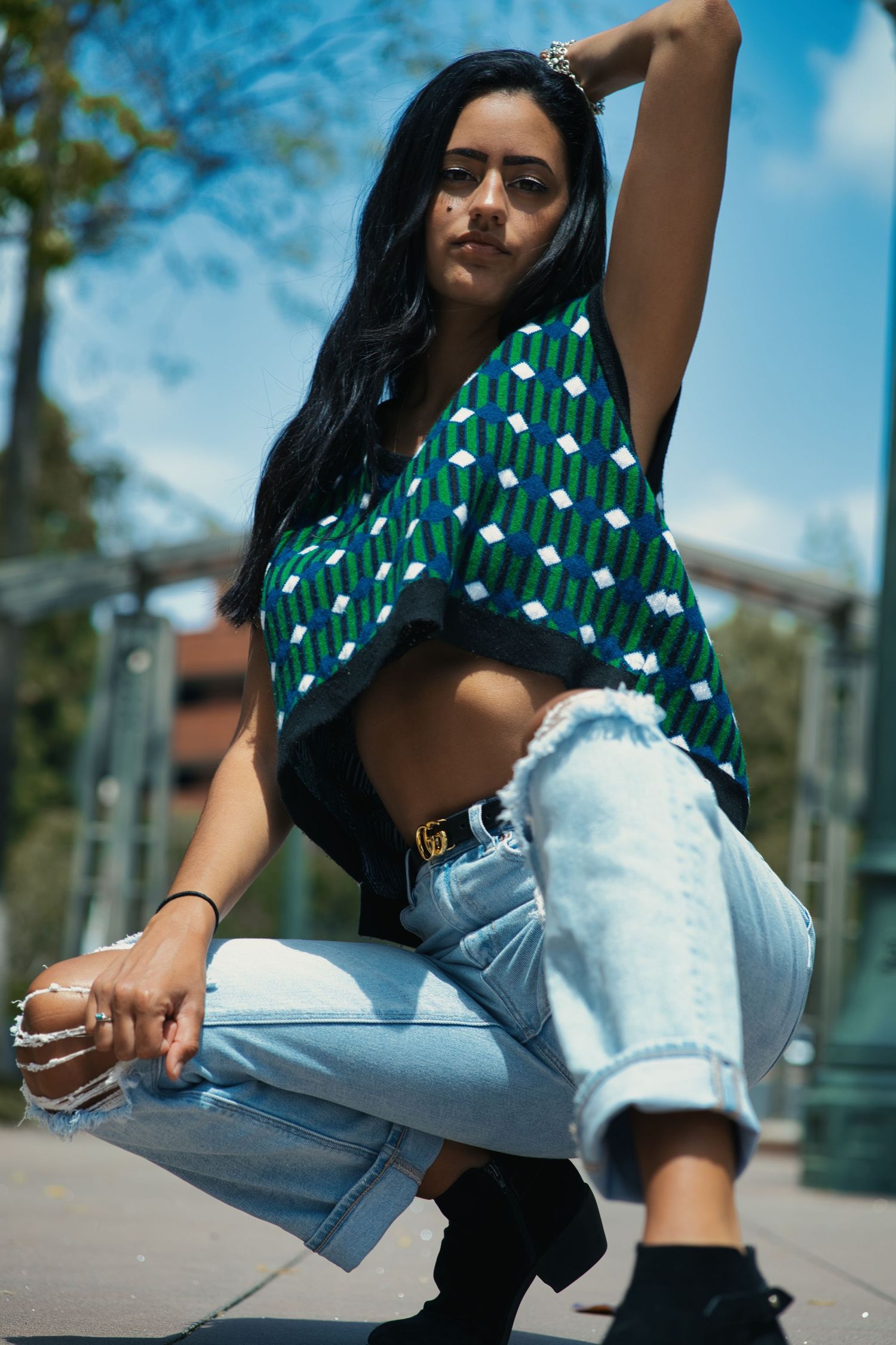 Stylish casual outfit with patterned crop top and light denim jeans in urban setting.