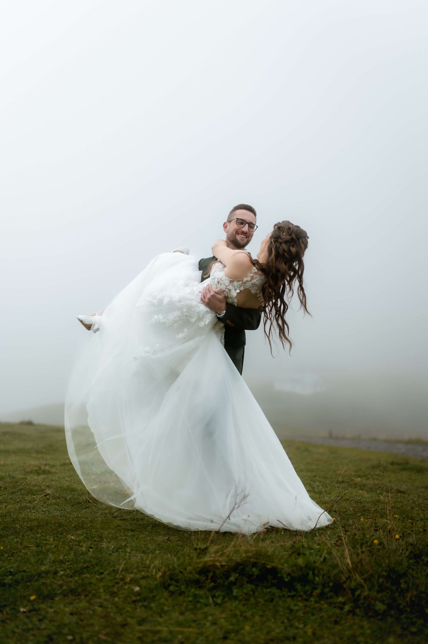 Der Bräutigam hebt seine Braut im Arm, umgeben von mystischem Nebel – Dina & Sebastian bei ihrem emotionalen Hochzeitsshooting in Vorarlberg