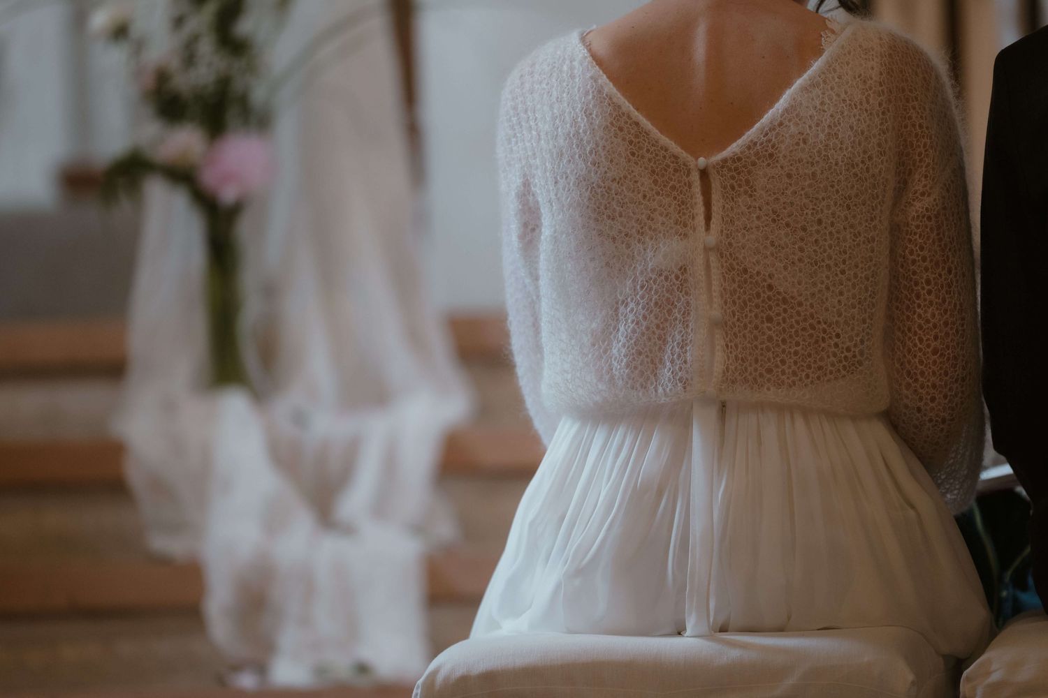 Rückenansicht der Braut im Brautkleid mit Strickjäckchen während der Trauung in Vorarlberg