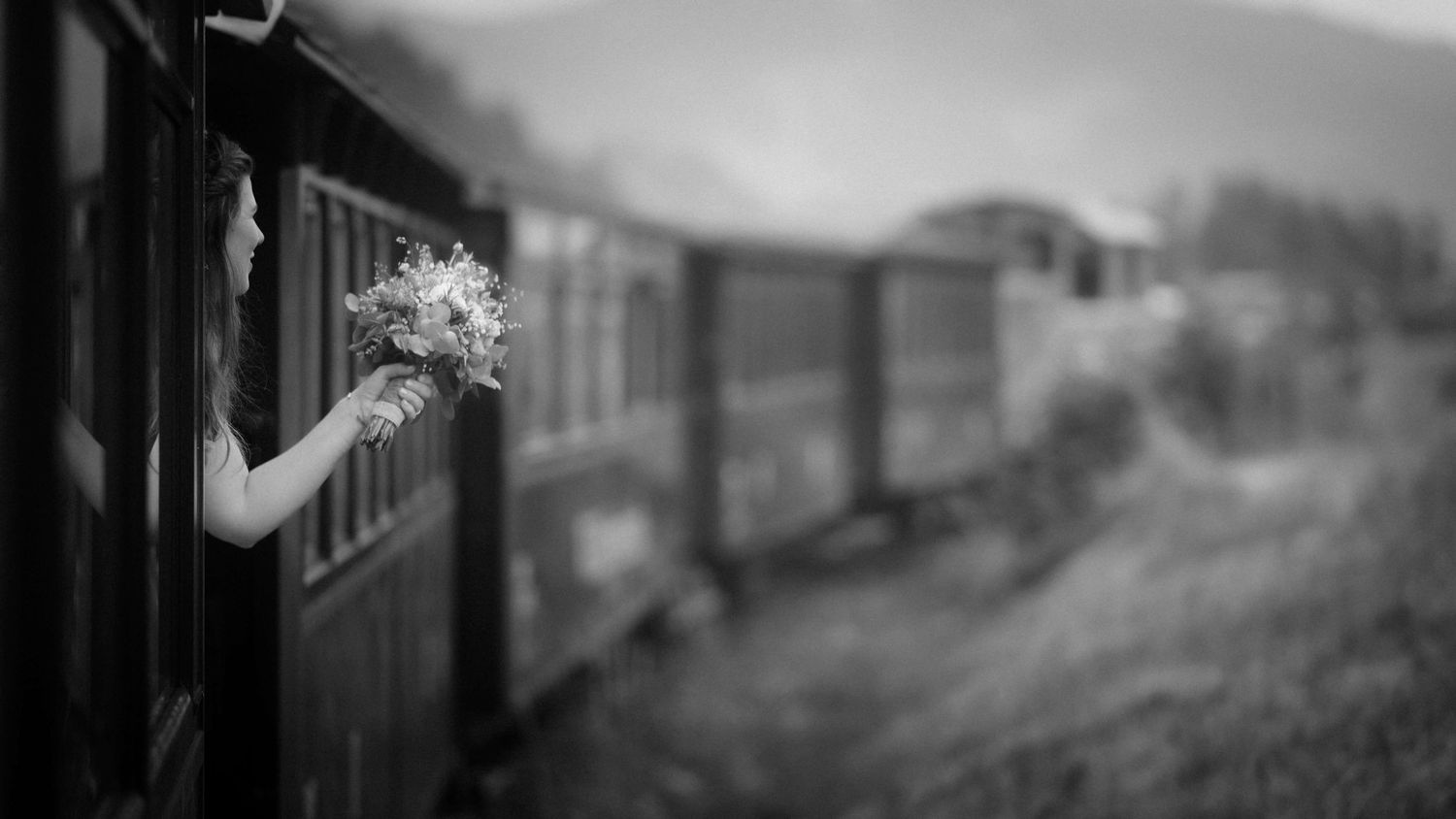 Die Braut streckt ihren Strauß aus dem Fenster eines nostalgischen Zugs – kreative und ungestellte Hochzeitsreportage in Vorarlberg.