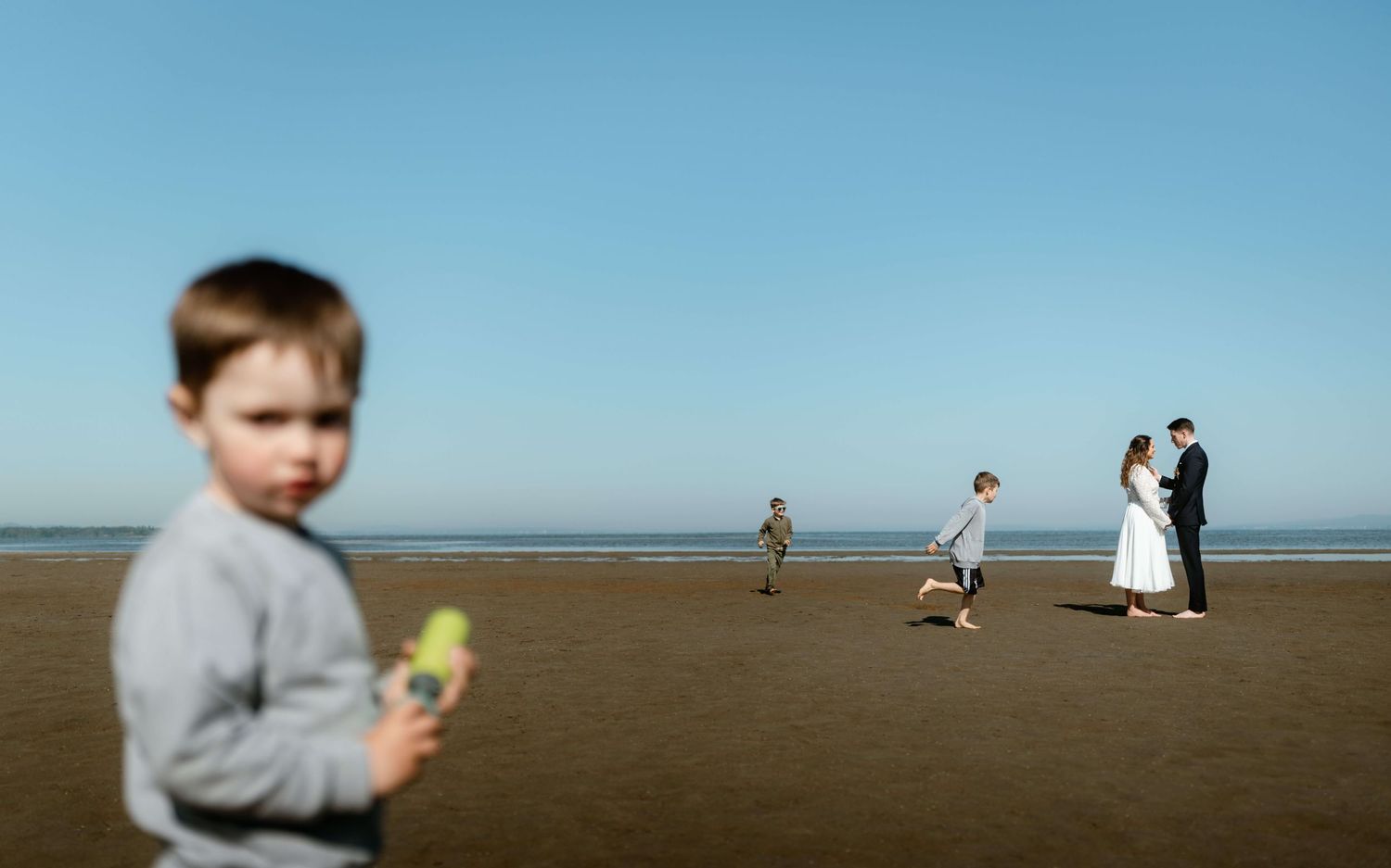 Natürliches Hochzeitsfoto von Jacqueline & Clemens mit ihren spielenden Kindern am Bodensee – dokumentarische Reportage von NuMa Fotografie