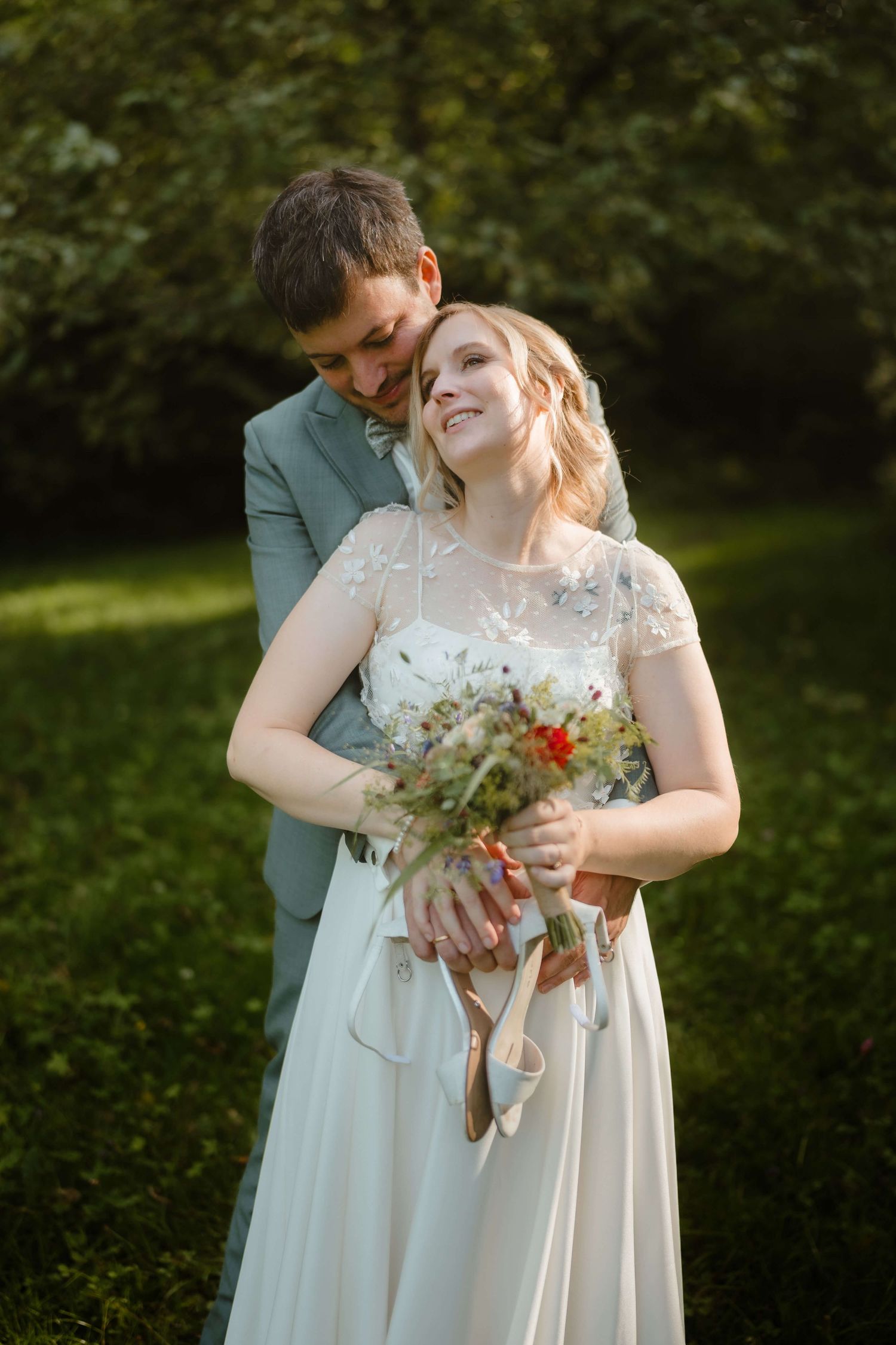 Verliebter Blick der Braut, mit wildem Brautstrauß und Schuhen in der Hand – festgehalten bei einer Hochzeit in Vorarlberg durch NuMa Fotogr
