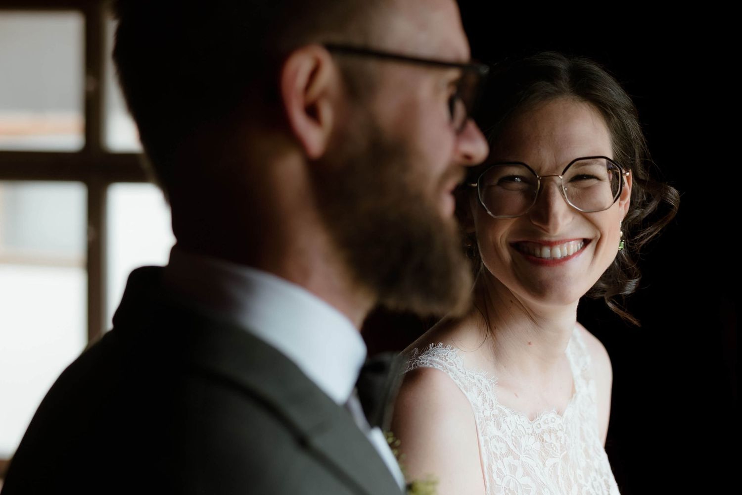 Lächelnde Braut mit Bräutigam im Vordergrund – ein echter Glücksmoment, dokumentiert von NuMa Fotografie bei einer Hochzeit in Vorarlberg