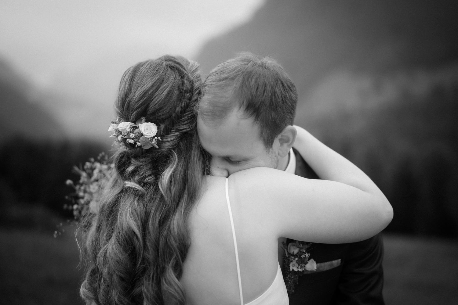 Stefan küsst Jasmin liebevoll auf einer Bergwiese in Vorarlberg – emotionaler Hochzeitsmoment in der Natur