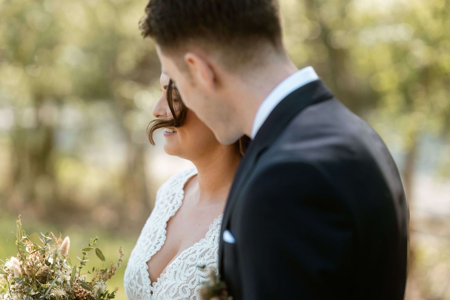 Der Bräutigam lehnt sich liebevoll zu seiner Braut, eine Haarsträhne im Wind – Hochzeitsshooting in Vorarlberg am Bodensee mit NuMa Fotograf