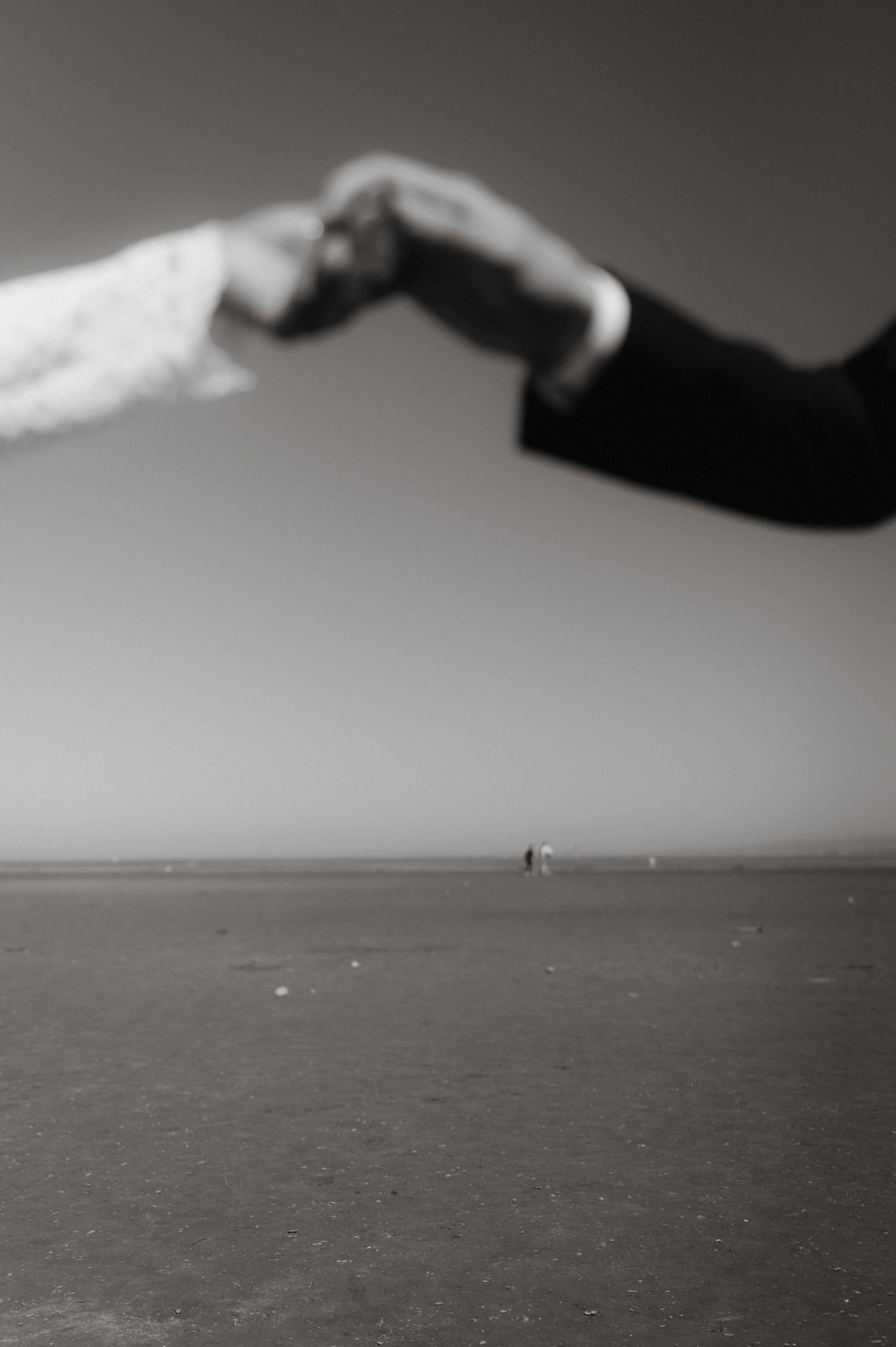 Braut und Bräutigam Hand in Hand in klassischer Schwarzweiß-Optik am Strand