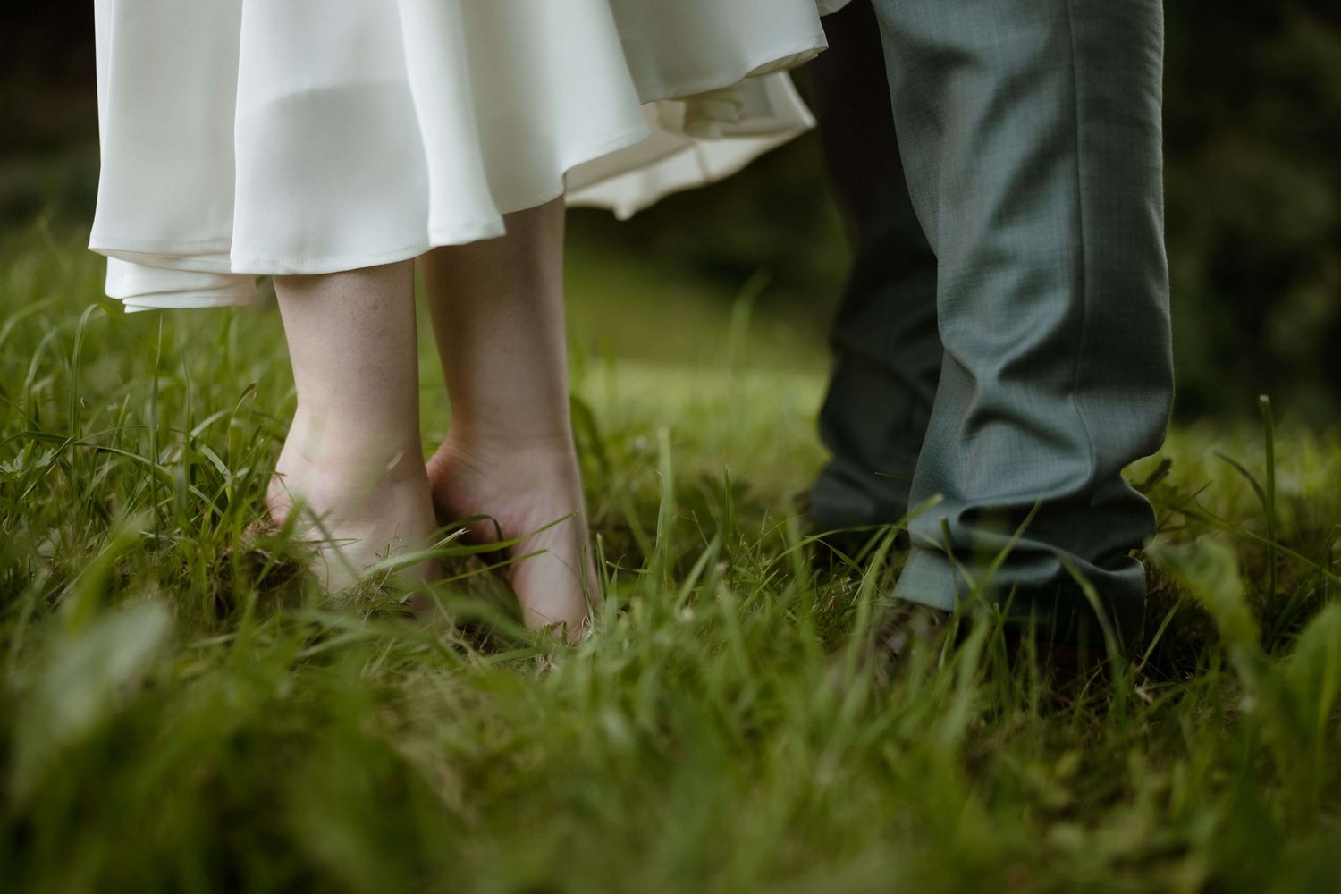 Detailaufnahme von Braut und Bräutigam barfuß im Gras – natürliche Hochzeitsfotografie in Vorarlberg von NuMa Fotografie.