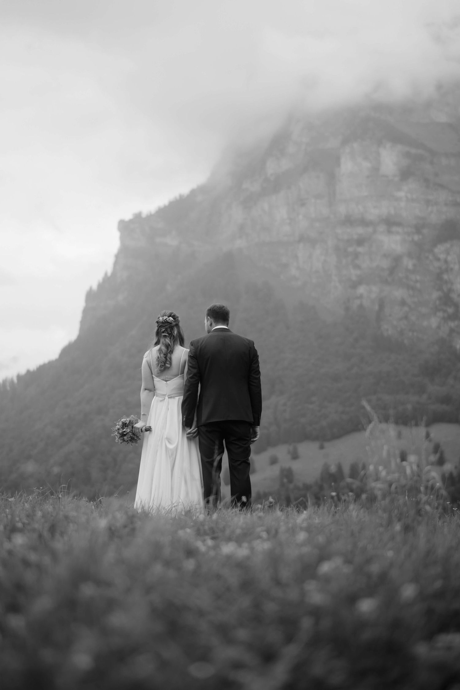 Das Brautpaar Jasmin und Stefan steht Hand in Hand mit Blick auf die majestätische Bergwelt Vorarlbergs – eine Szene voller Ruhe und Tiefe.